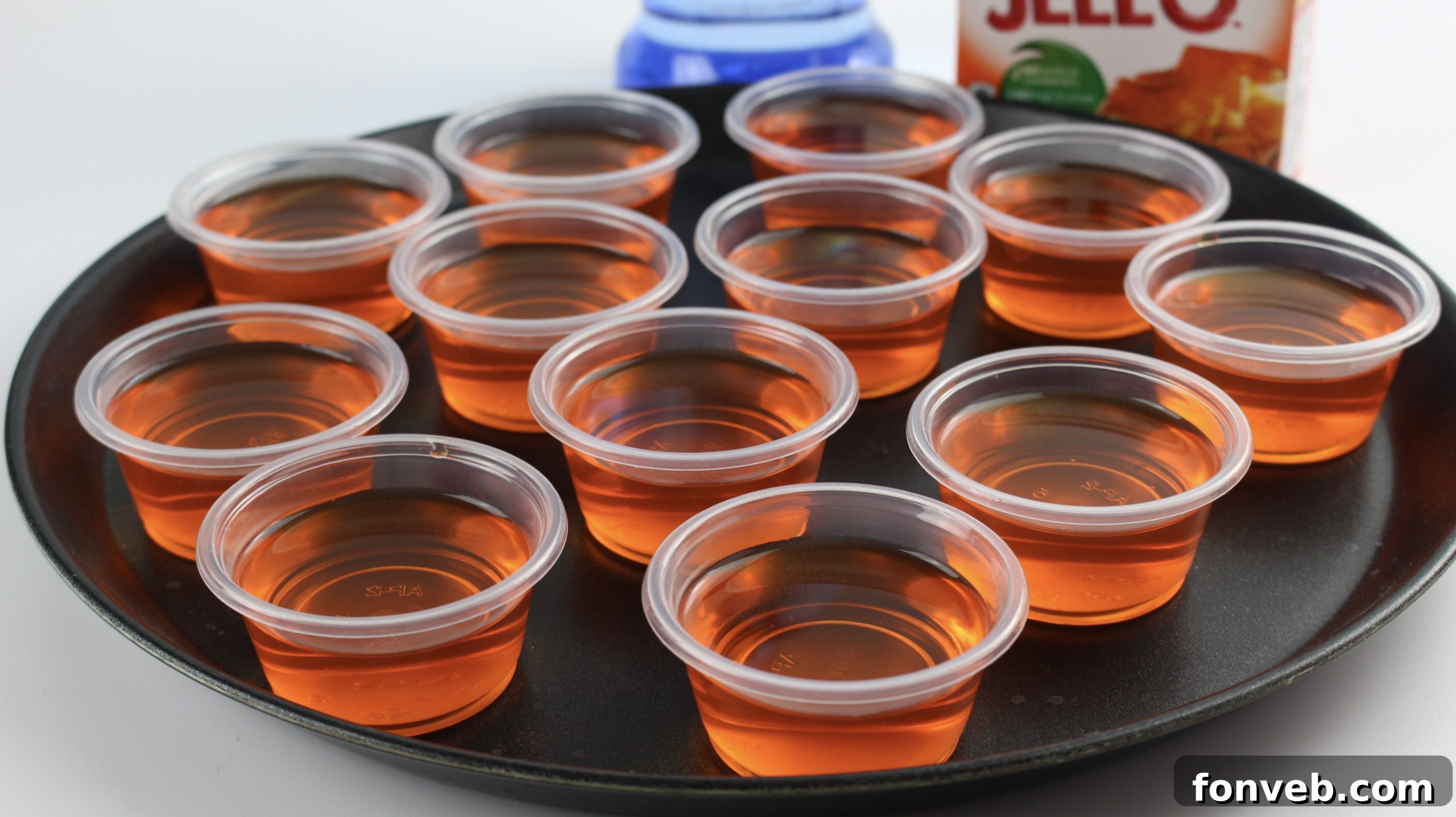 A tray of Orange Creamsicle Jello Shots, garnished with a swirl of white whipped cream.