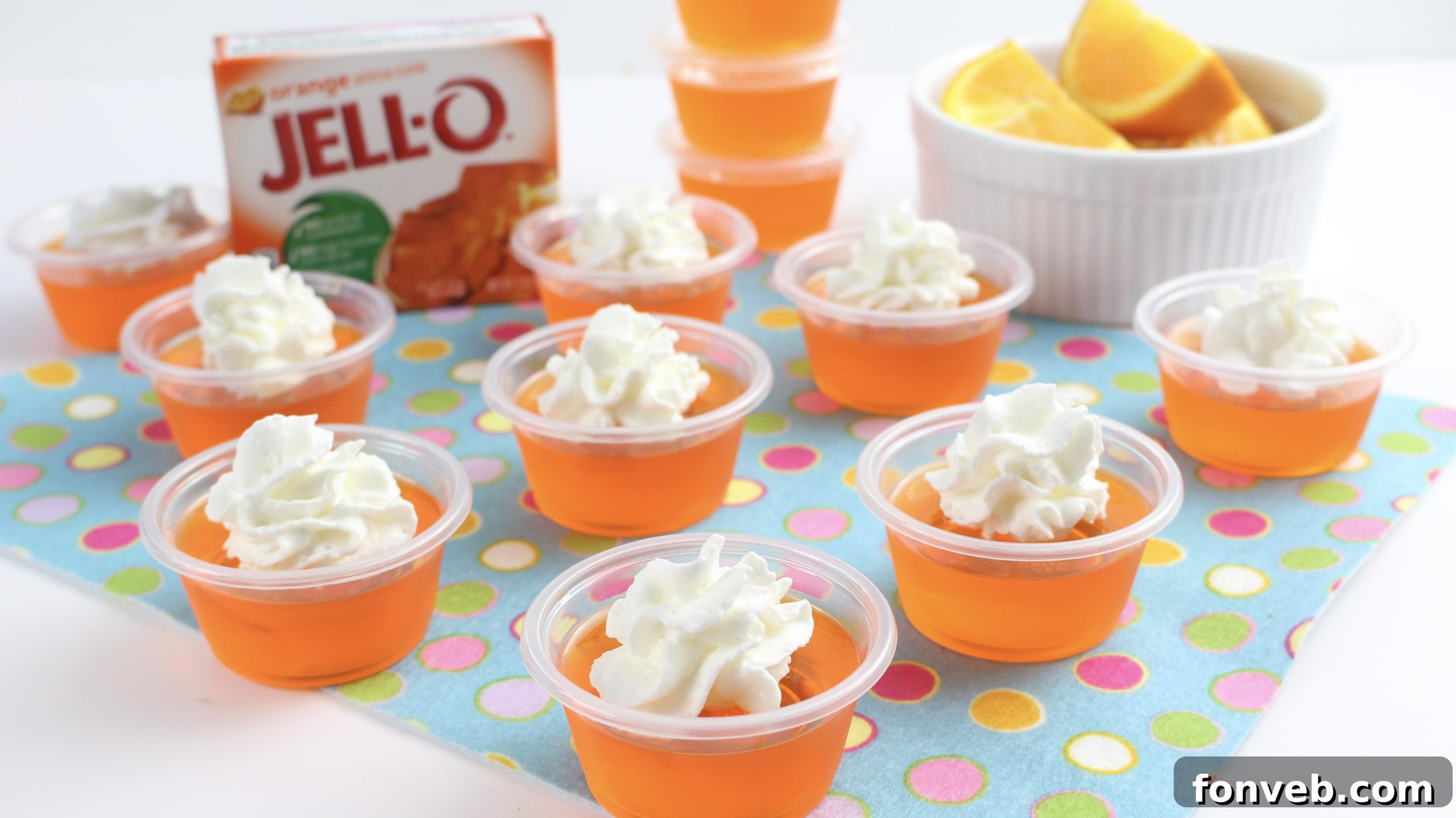 A close-up of a single Orange Creamsicle Jello Shot, topped with whipped cream, ready to be enjoyed.