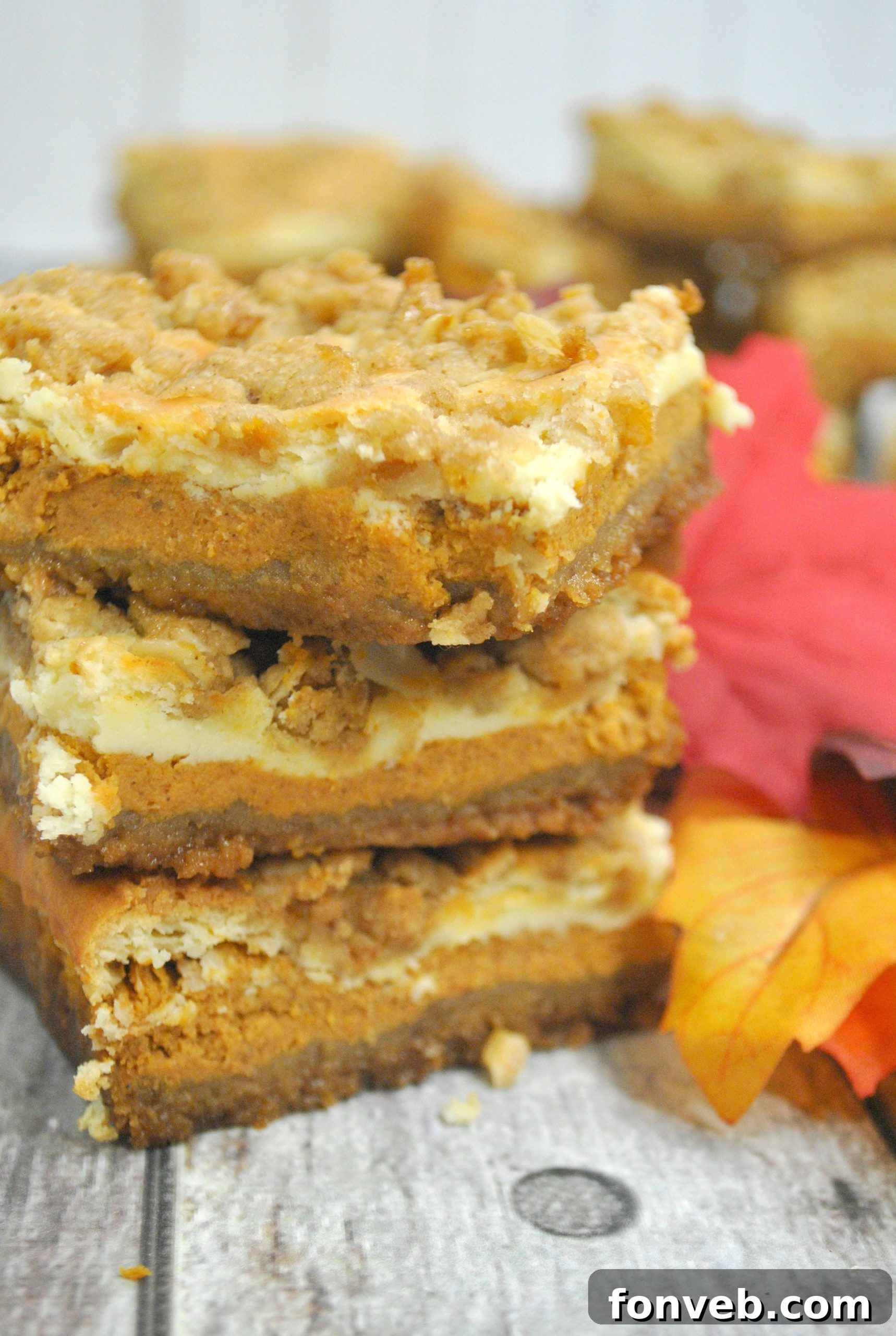 Harvest Pumpkin Crumble Cheesecake Squares 2 Close-up of a perfectly baked pumpkin cheesecake bar with a crumbly streusel topping, showcasing the distinct layers of crust, cheesecake, and pumpkin filling.