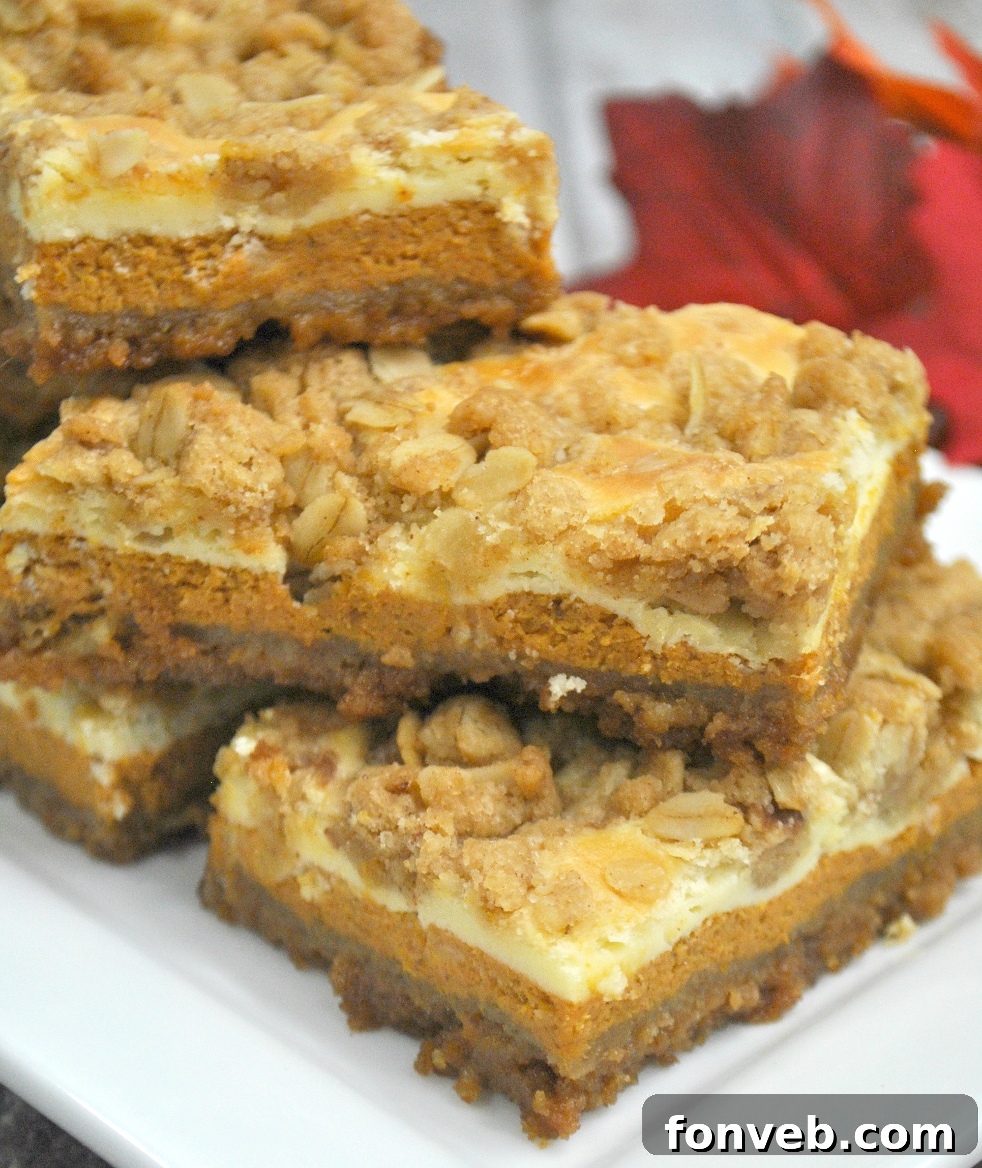 Harvest Pumpkin Crumble Cheesecake Squares 3 Two perfectly sliced pumpkin cheesecake bars presented on a rustic wooden surface, emphasizing the rich color and inviting texture of the streusel topping.