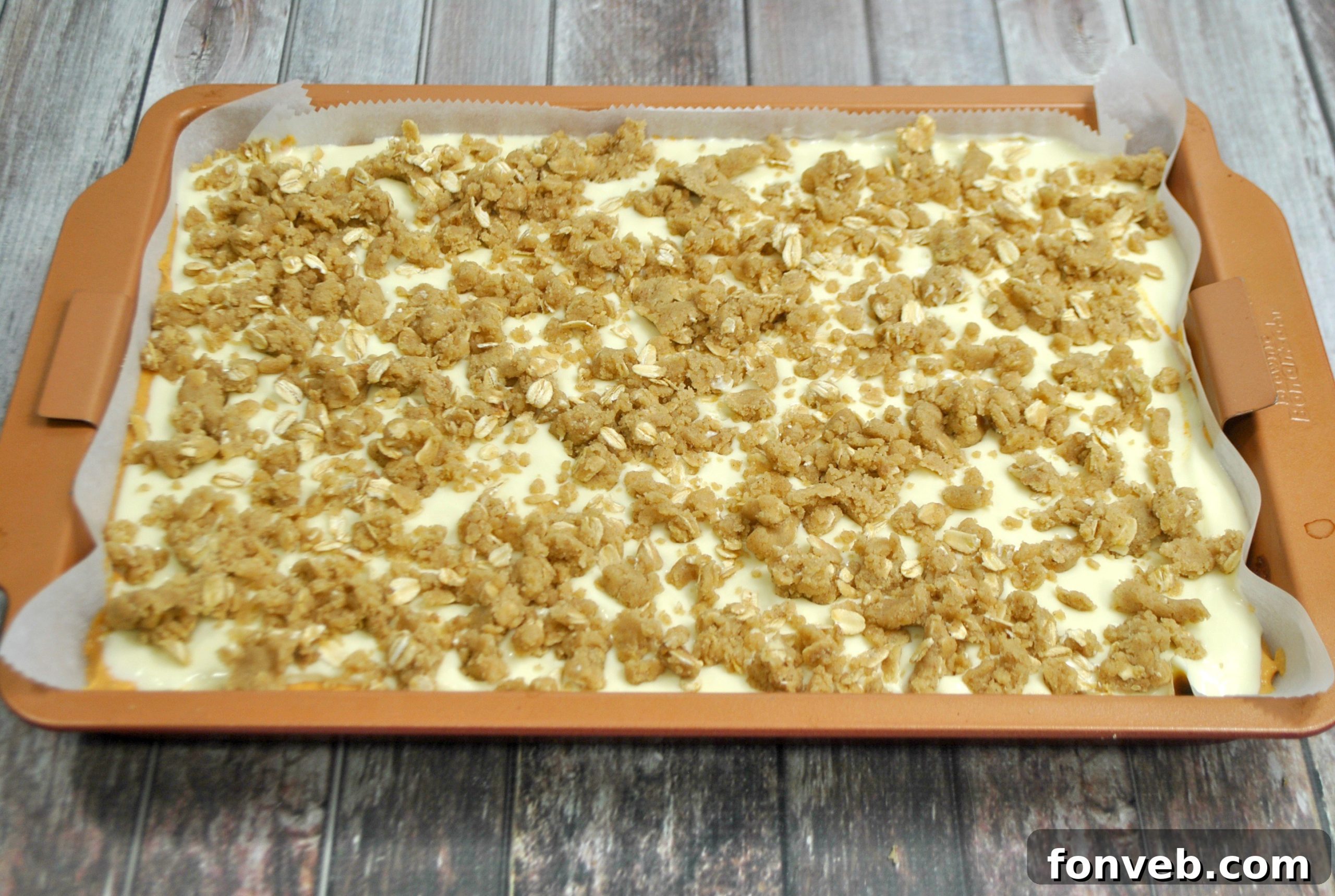 Harvest Pumpkin Crumble Cheesecake Squares 4 An overhead shot of a freshly baked tray of pumpkin cheesecake bars, highlighting the golden-brown streusel and the perfectly set filling, ready for cooling.