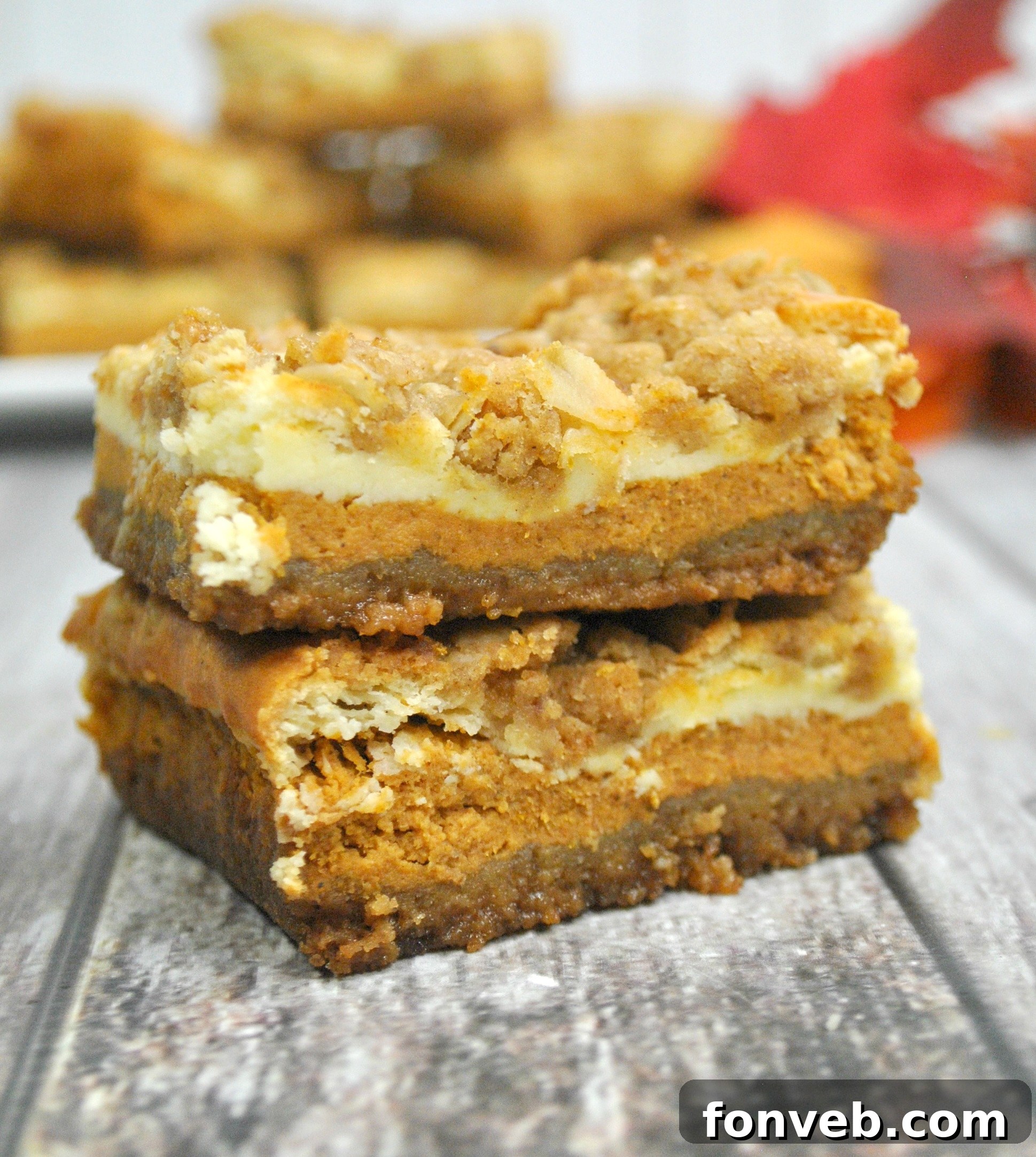 Harvest Pumpkin Crumble Cheesecake Squares 7 A beautifully presented serving tray filled with numerous pumpkin cheesecake bars, ready for a large gathering or celebration.