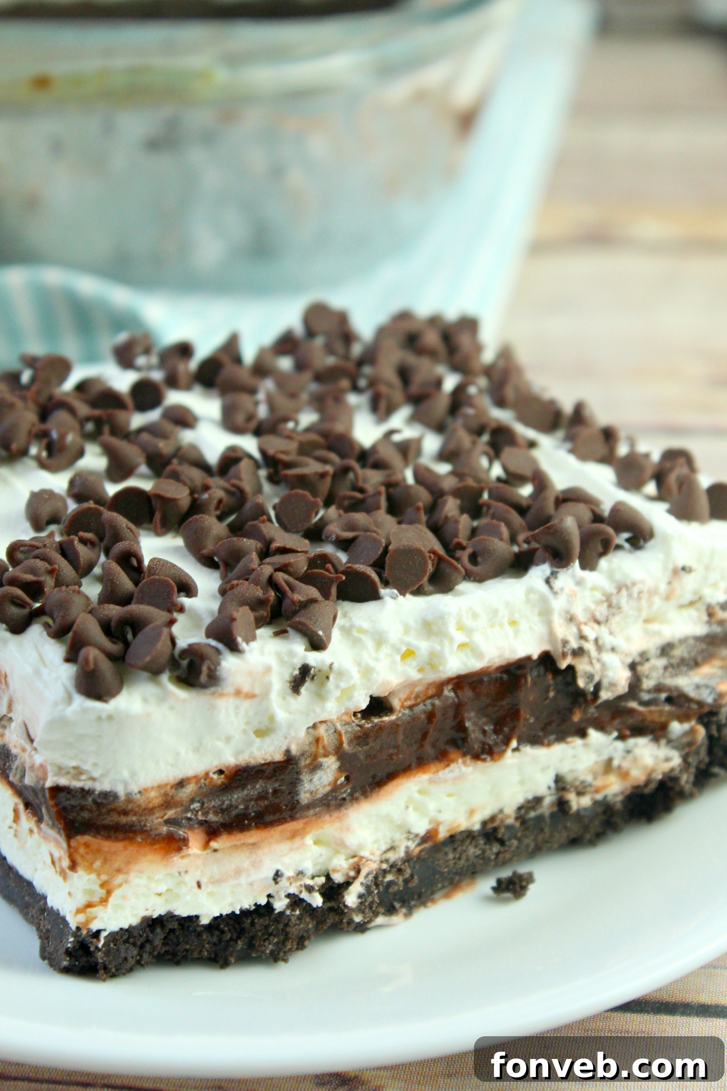 Delicious layers of No-Bake Chocolate Lasagna in a baking dish, showcasing the Oreo crust, cream cheese layer, chocolate pudding, and whipped topping.