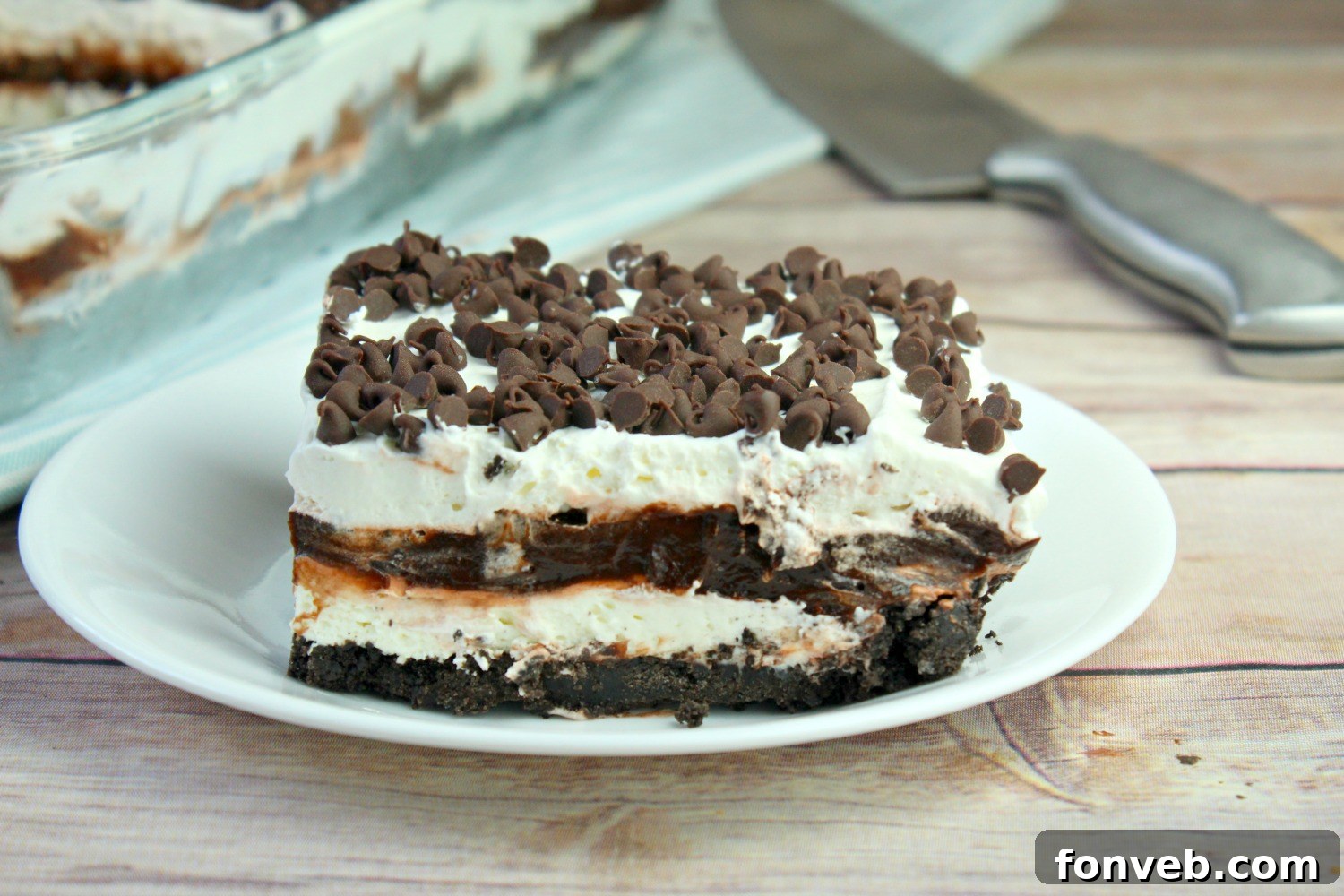 A side view of the No-Bake Chocolate Lasagna, highlighting the distinct layers of crust, cream cheese, pudding, and whipped topping with chocolate shavings.