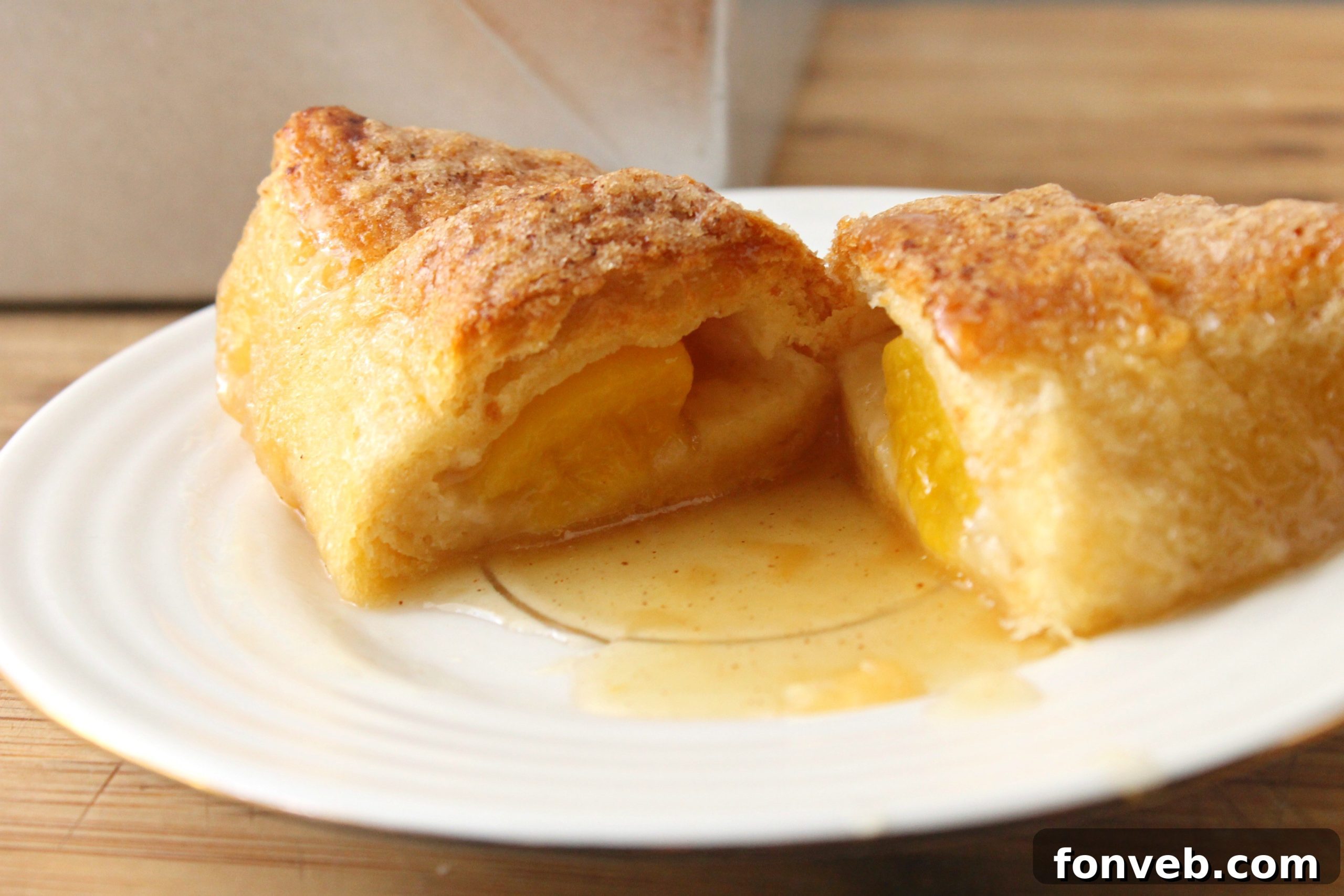Peachy Keen Dumplings 3 Close-up of golden peach dumplings with a rich, bubbling sauce in a baking dish.