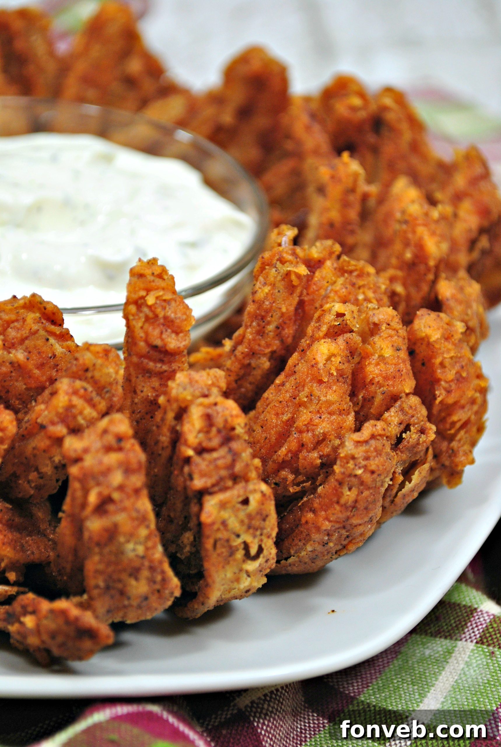 A bowl of creamy homemade Green Onion Ranch Dip, garnished with fresh green onions, perfectly complementing the crispy Bloomin' Onion.