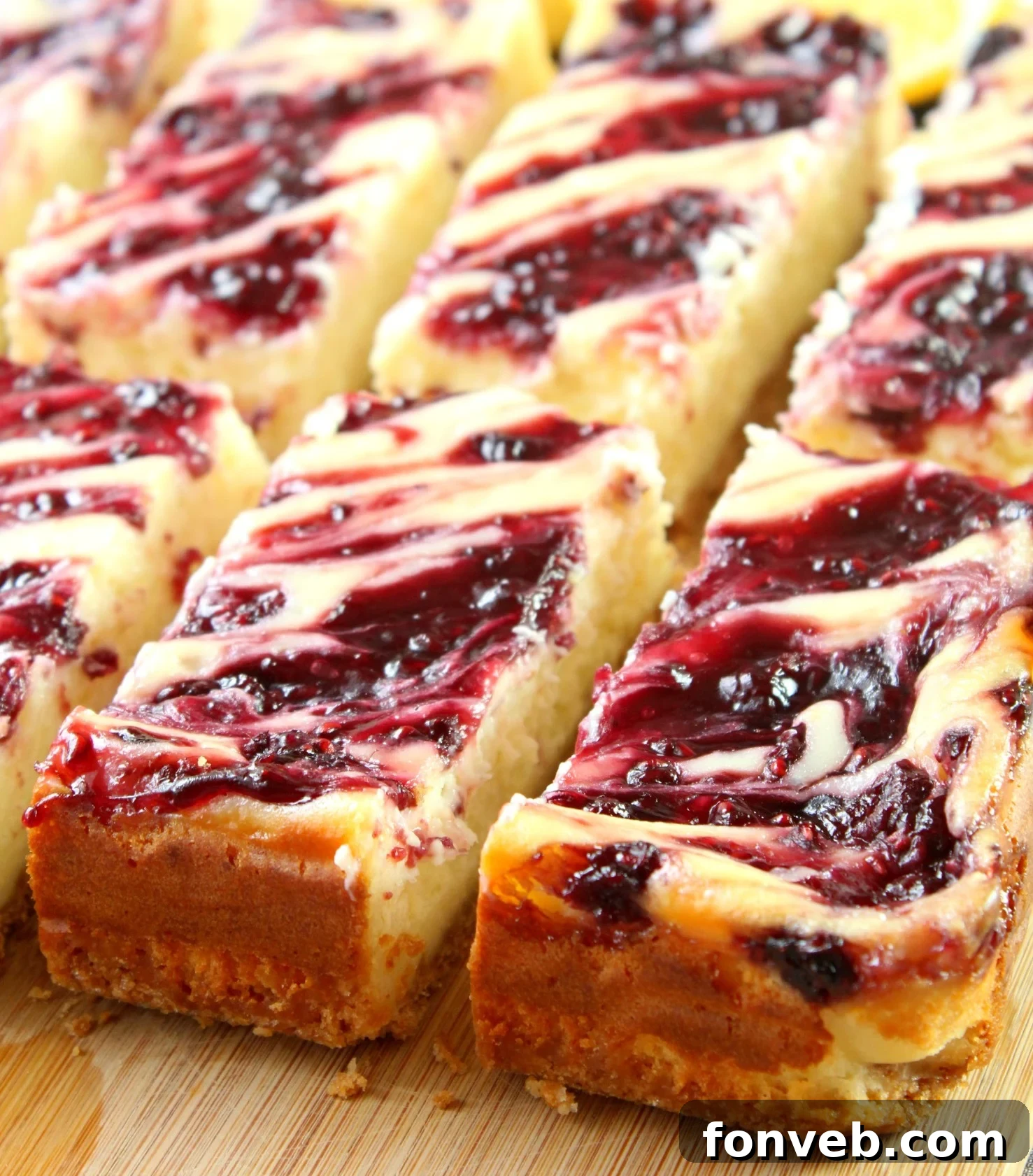 Close-up of a square lemon raspberry cheesecake bar with a swirl of raspberry filling on top, resting on parchment paper. The bar displays a perfect crumbly crust, creamy white cheesecake layer, and a rich red raspberry swirl.