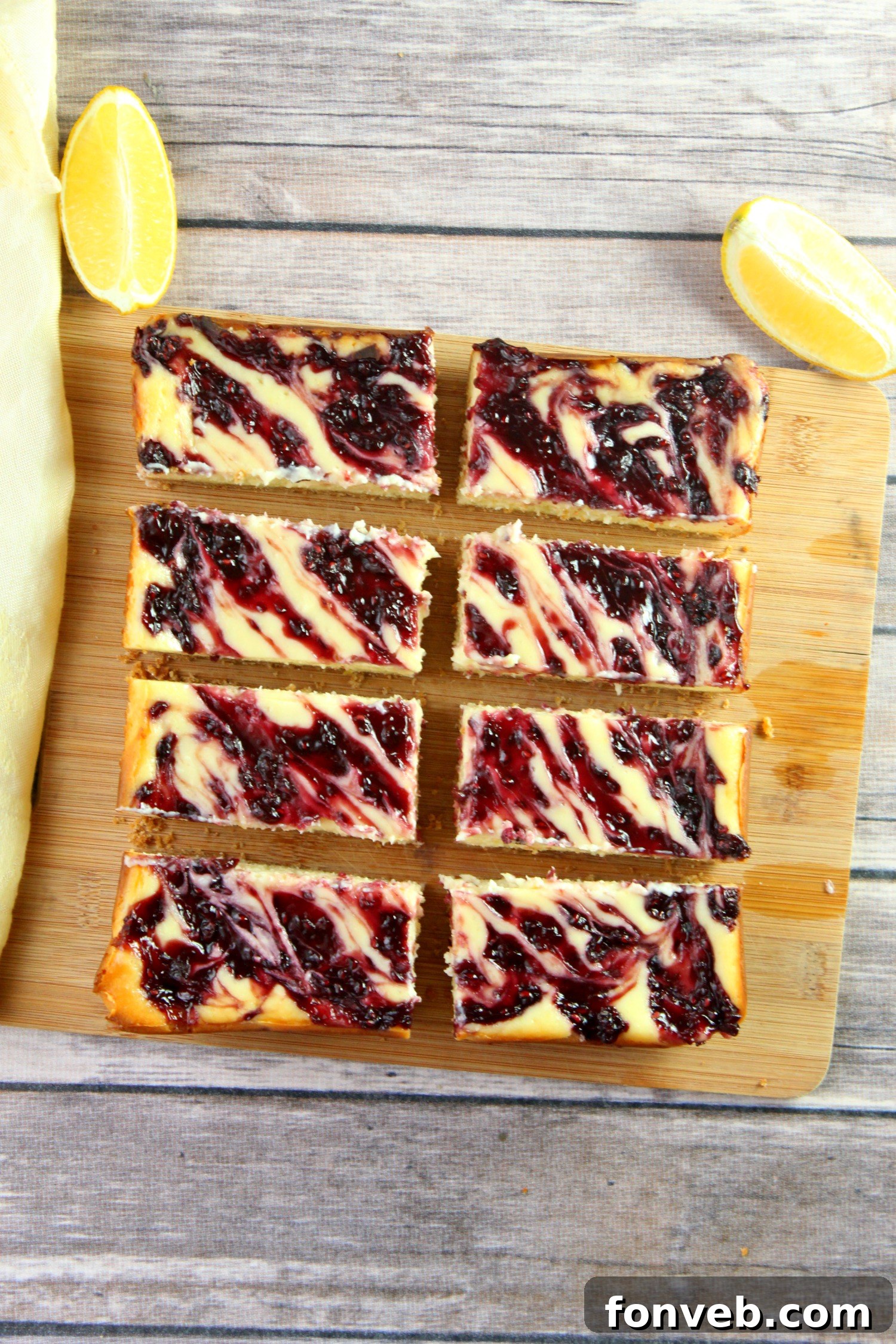 An overhead shot revealing a full pan of warm lemon raspberry cheesecake bars, freshly baked with artful swirls of raspberry filling, ready to cool and set.