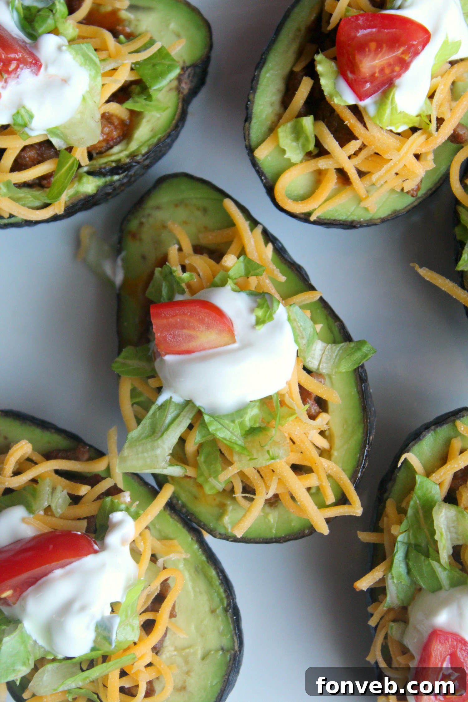 Close-up of a single taco stuffed avocado half, showcasing the colorful filling of seasoned beef, cheese, and fresh vegetables