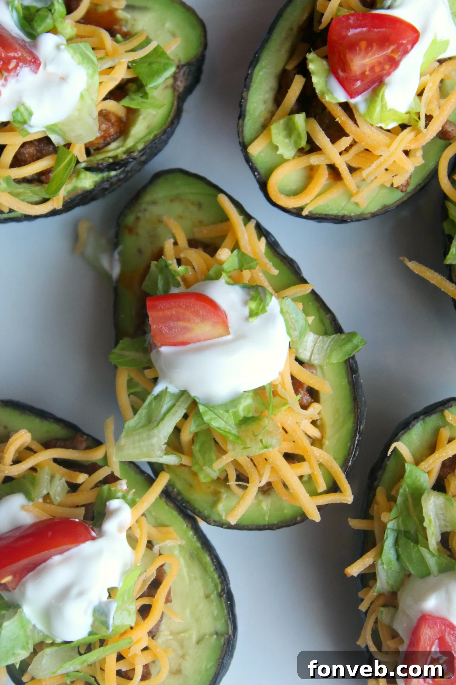 Three taco stuffed avocado halves arranged attractively on a platter, ready to be served