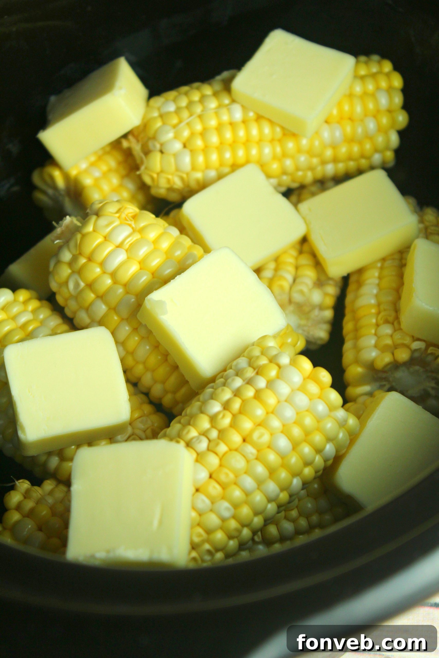 Cooked corn on the cob with a serving spoon