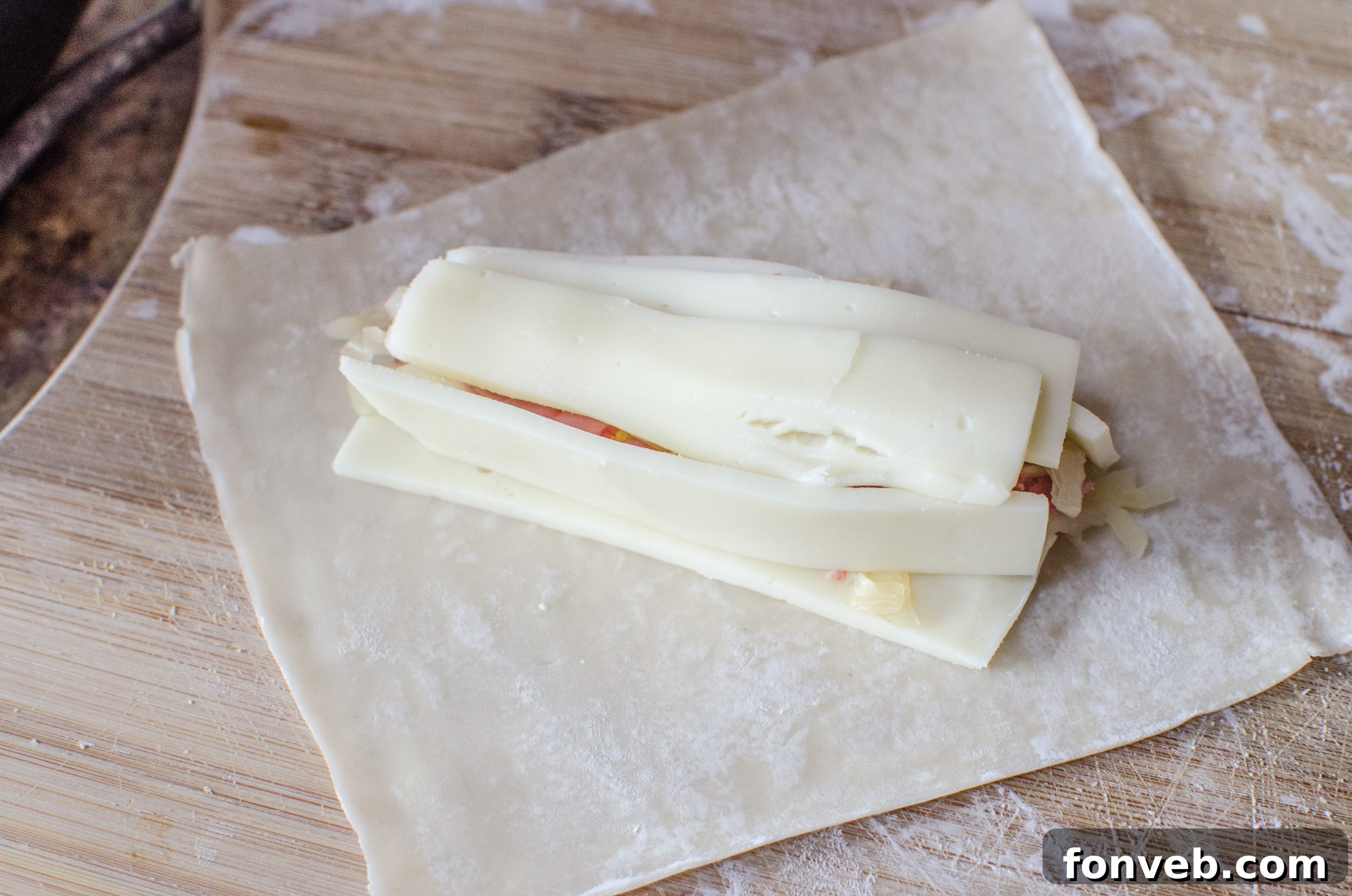 Hands demonstrating the simple folding technique for wrapping Reuben Egg Rolls, showing the filling secured inside.