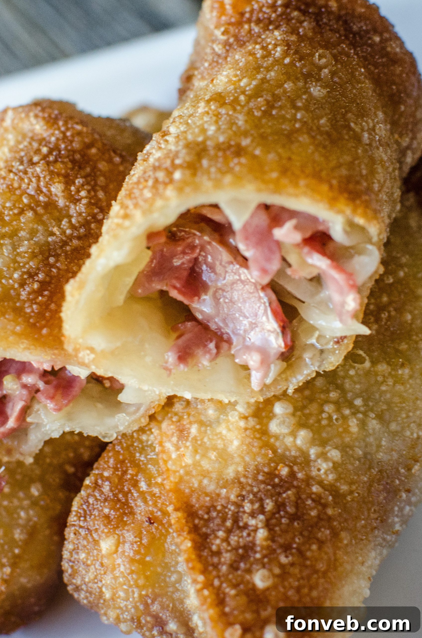 A single Reuben Egg Roll, perfectly fried to a golden crisp, with a small dish of mustard for dipping.