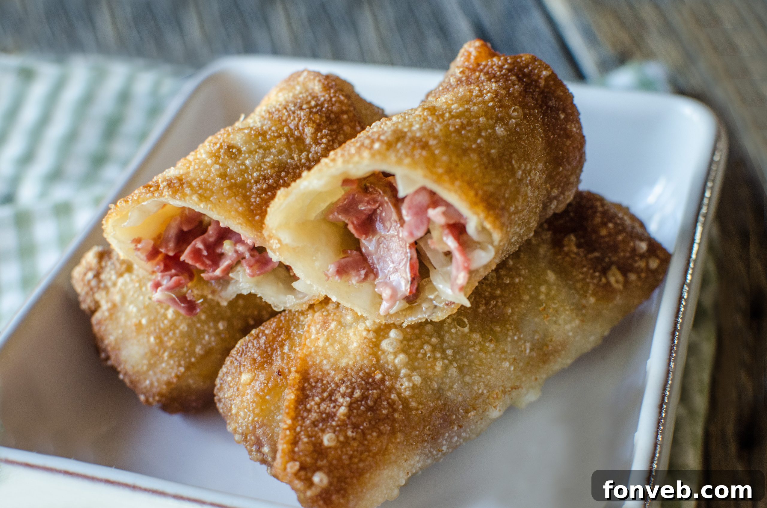Close-up of a cut Reuben Egg Roll, revealing the warm, melty Swiss cheese, corned beef, and sauerkraut filling.