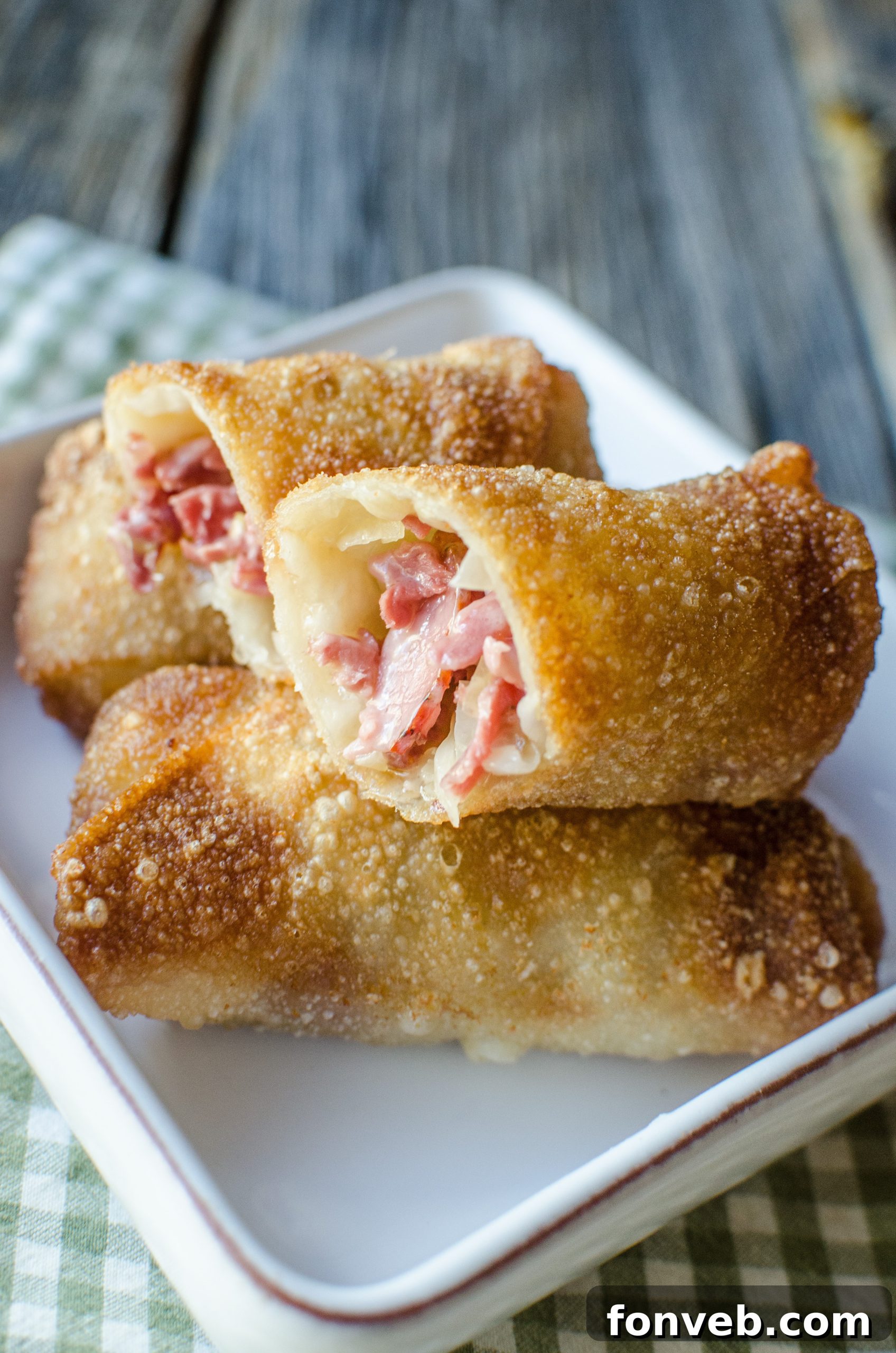 A vibrant display of multiple Reuben Egg Rolls, some whole and some cut, showcasing their delicious interior.