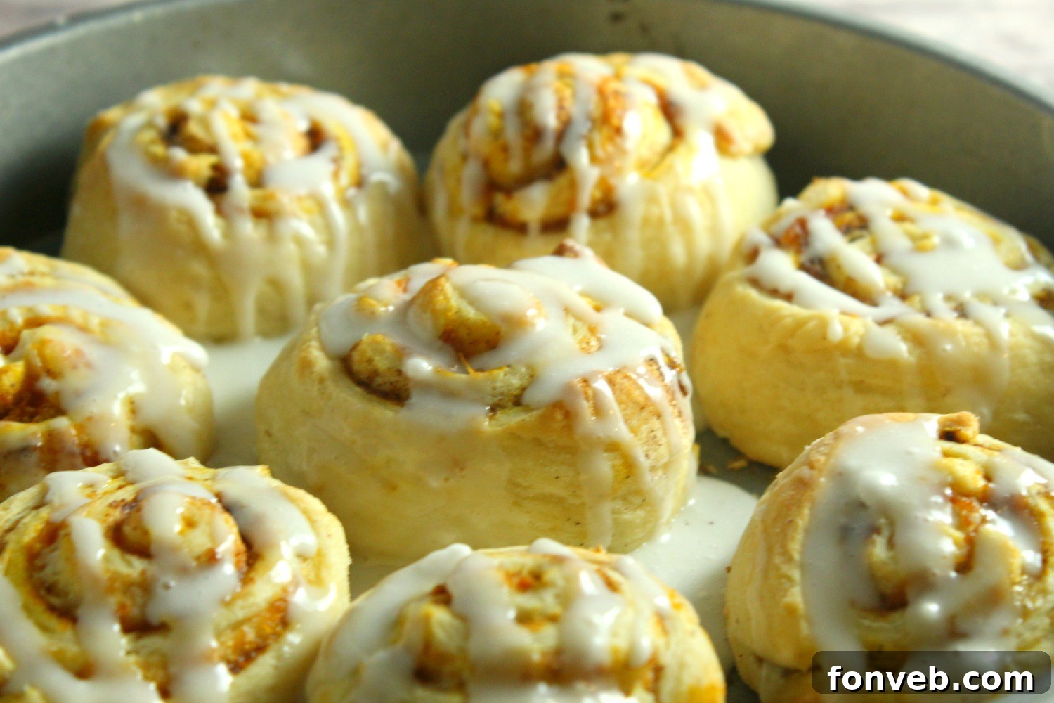 A top-down view of a single pumpkin cinnamon roll, showcasing its soft texture and generous cream cheese frosting.