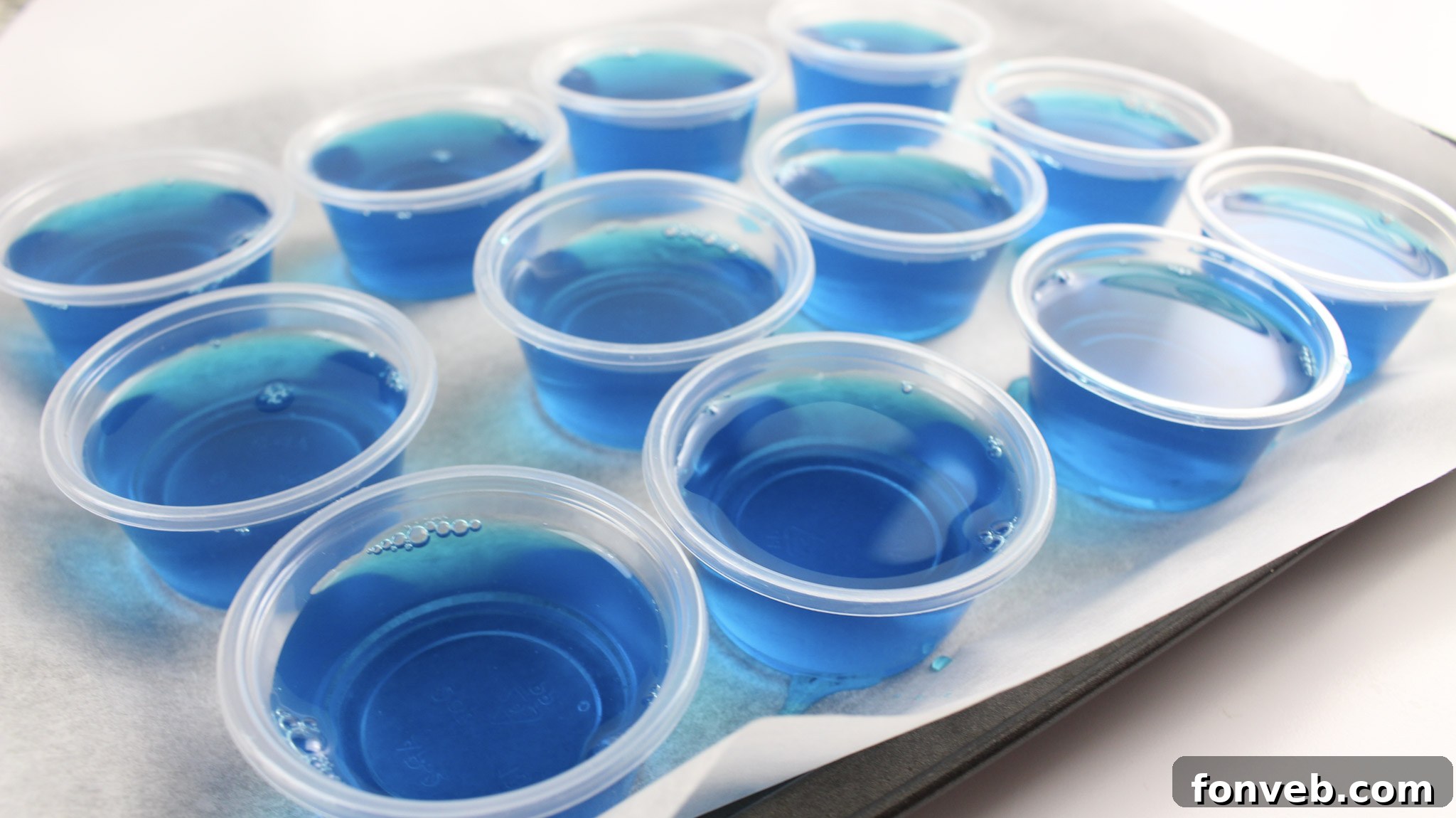 Rows of Blue Hawaiian Jello Shots neatly arranged in small plastic cups, ready to be served at a lively party or themed gathering.