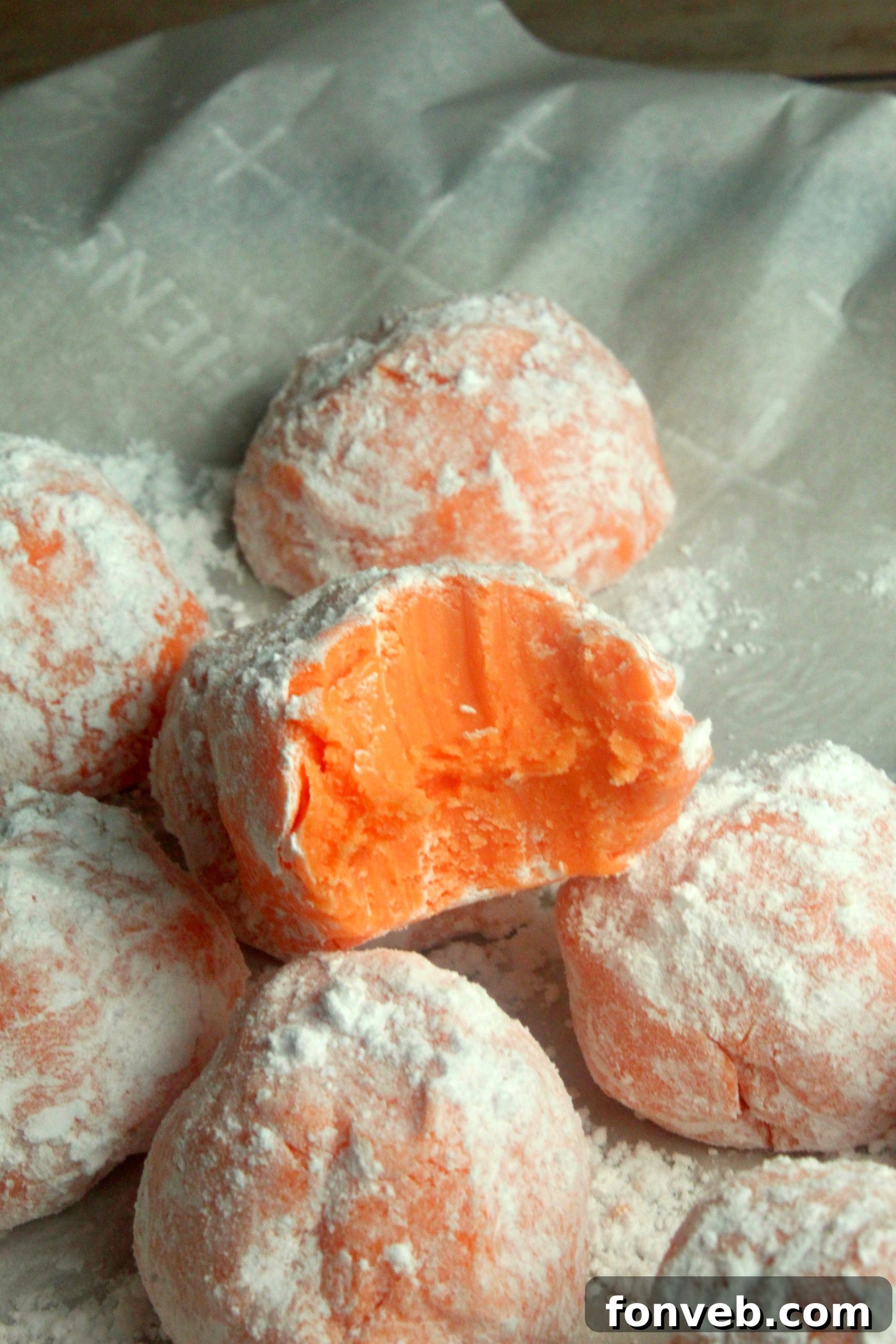 Sunny Orange Creamsicle No Bake Bites 5 A selection of orange creamsicle truffles dusted with a fine layer of powdered sugar on a decorative plate.
