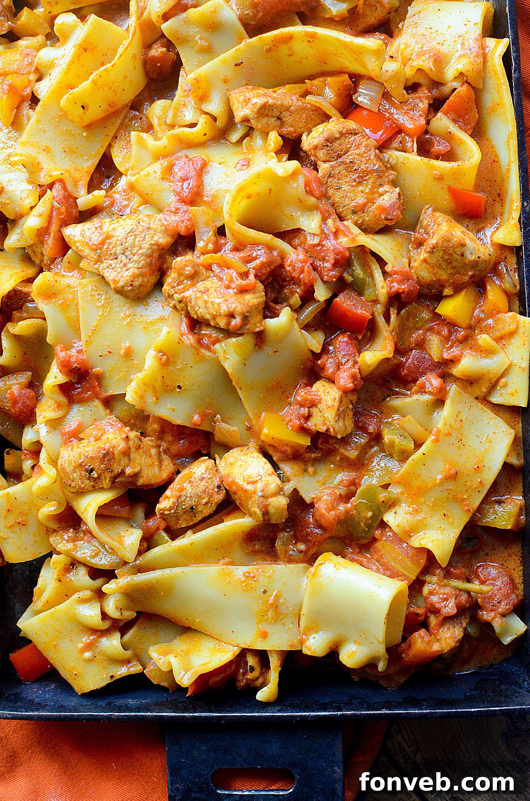 Pasta simmering in a rich, creamy sauce with fajita vegetables in a large skillet