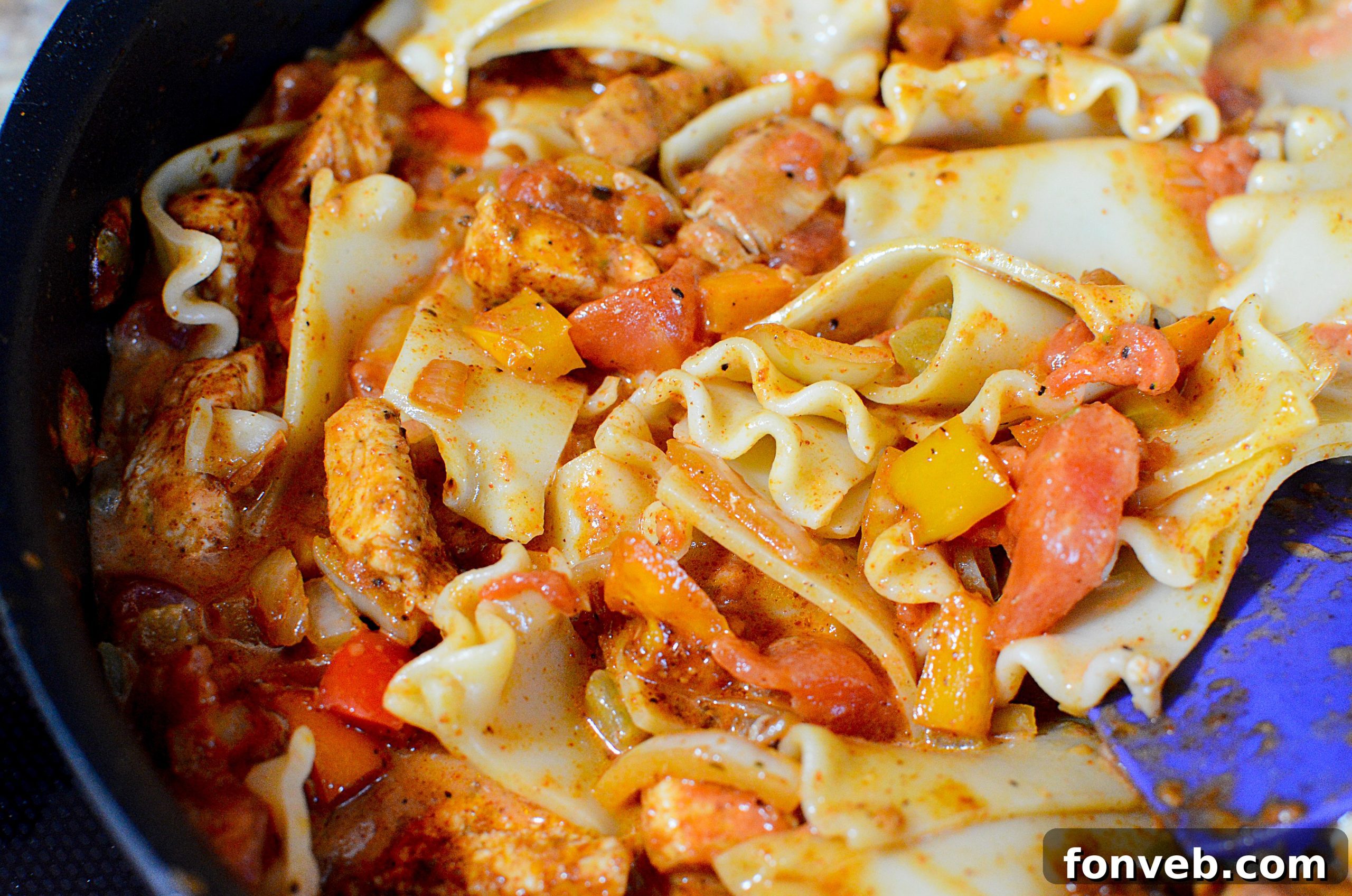 A collection of fresh ingredients for chicken fajita pasta, including chicken, bell peppers, onion, and spices