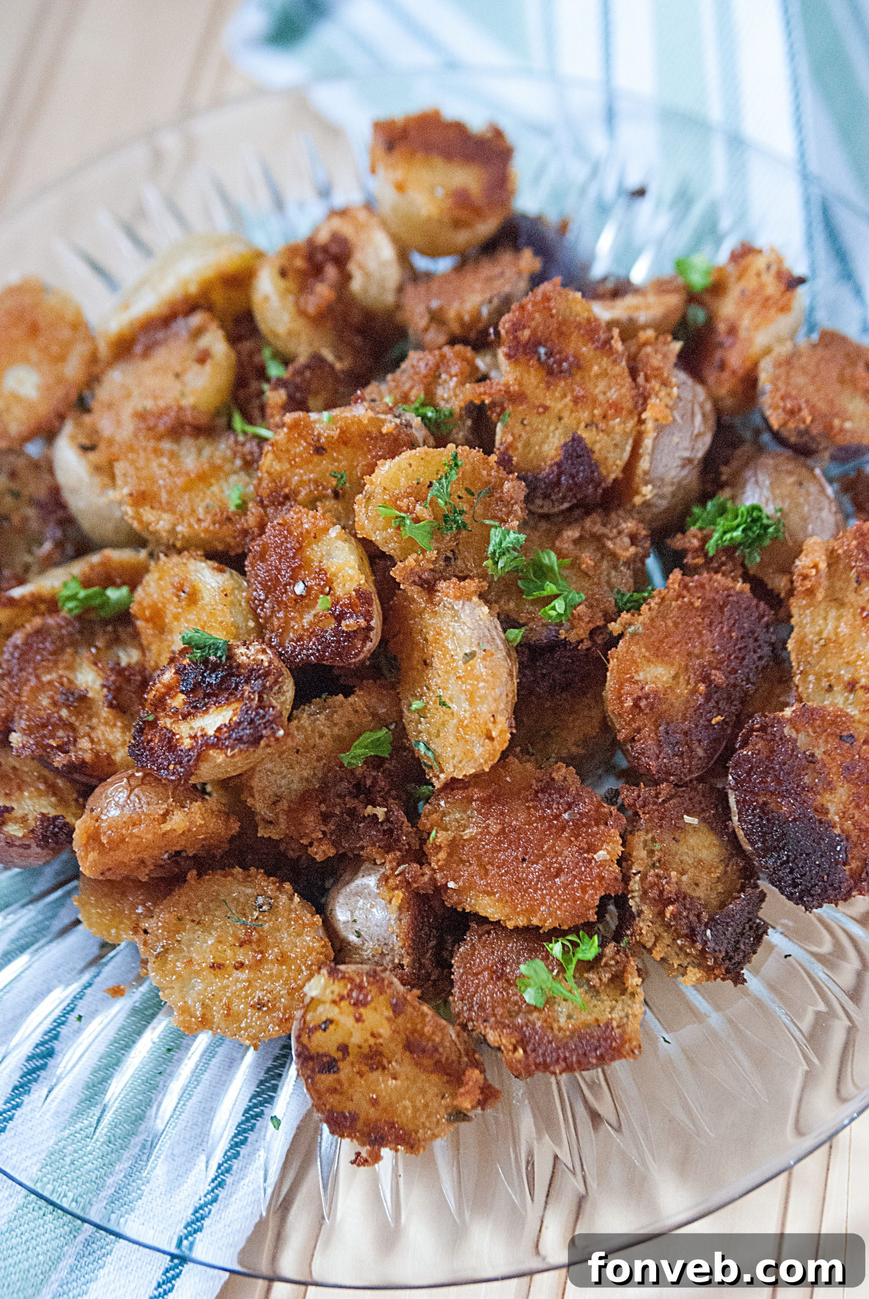 A serving of Crispy Garlic Parmesan Potatoes on a plate next to a main course.