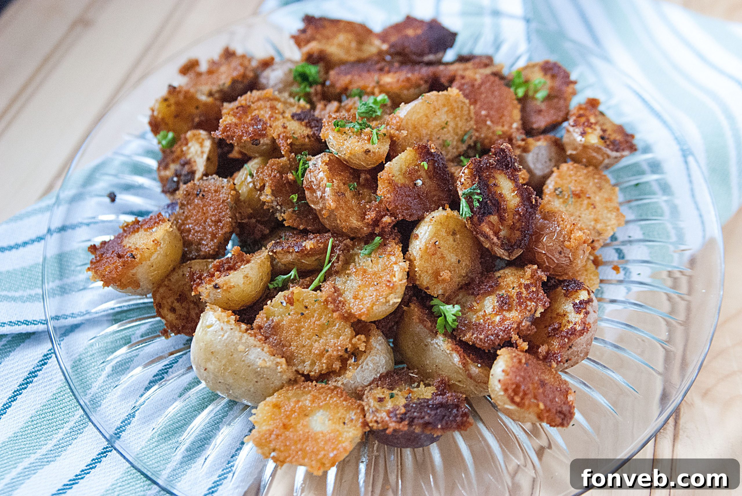 Hands scoring small potatoes with a knife before seasoning.