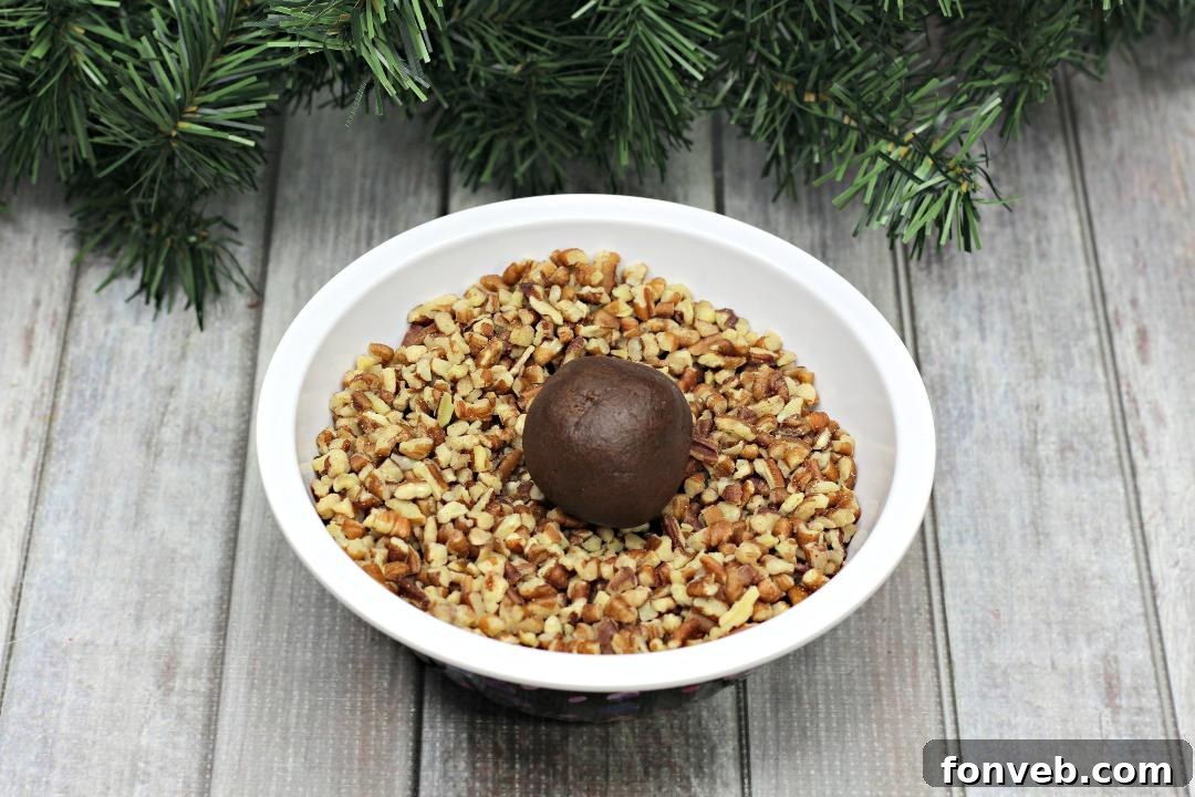 Chewy Turtle Thumbprint Delights 4 Pecan-coated chocolate cookie dough balls on a baking sheet, ready for baking.