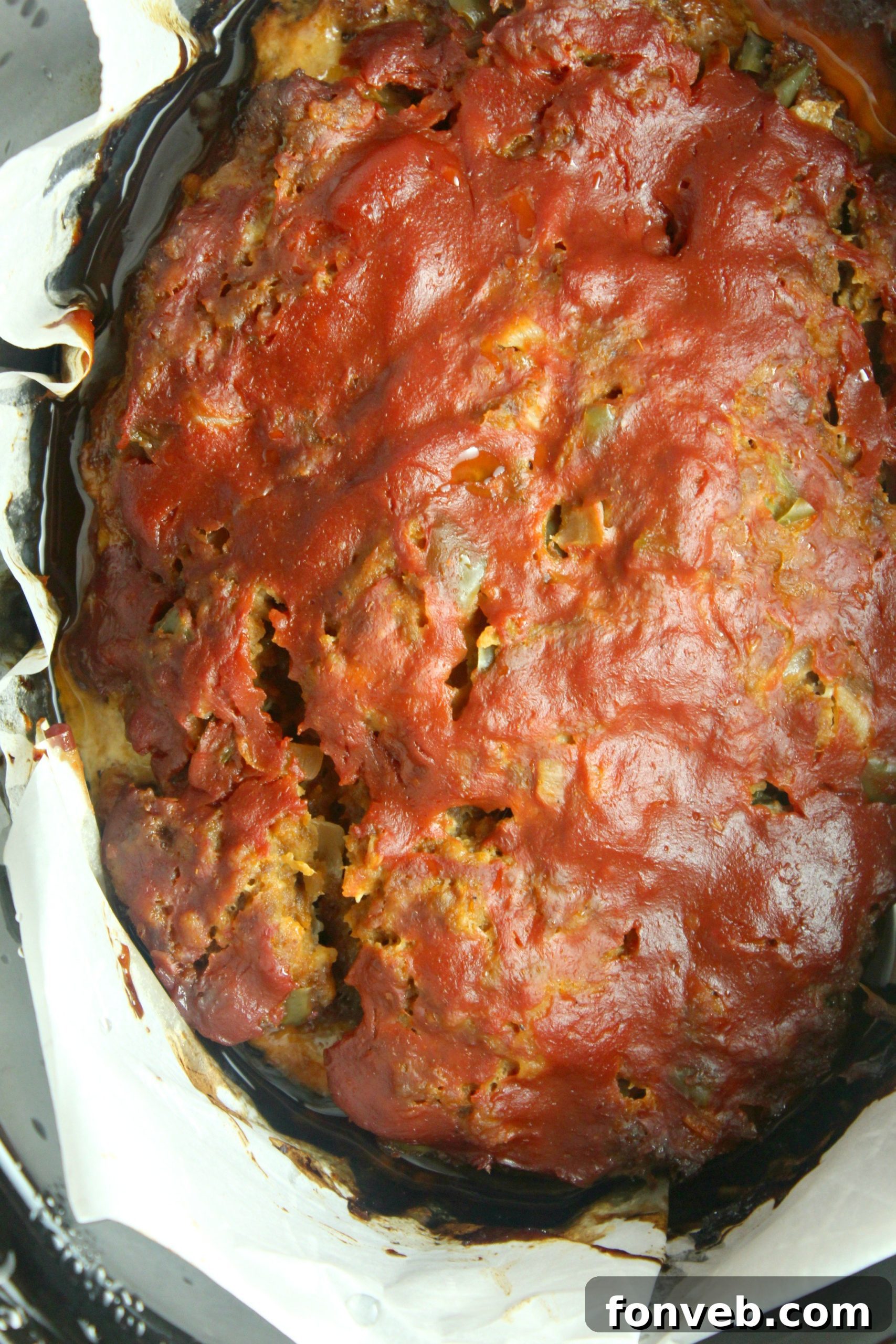 A full slow cooker meatloaf, ready to be sliced and served, bathed in its delicious sauce.