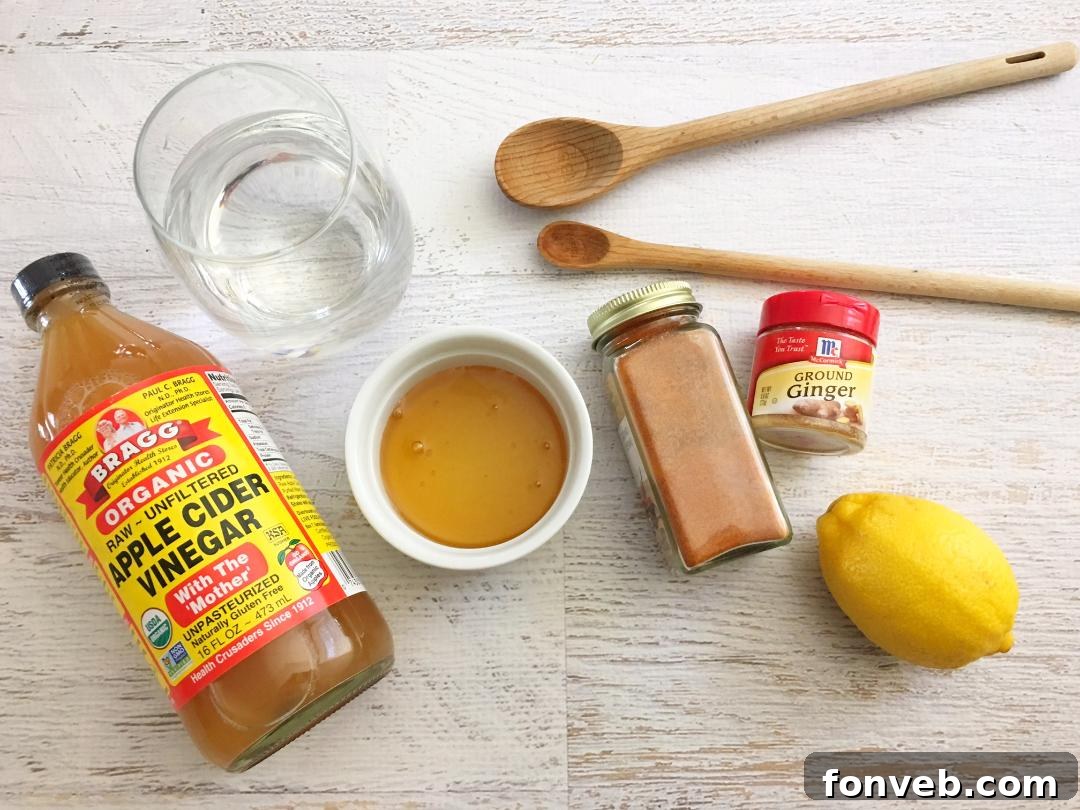 A mason jar of homemade cough syrup next to a sliced lemon and honey.