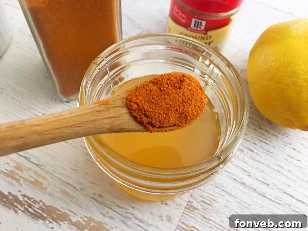 A close-up of a hand holding a spoonful of homemade cough syrup.