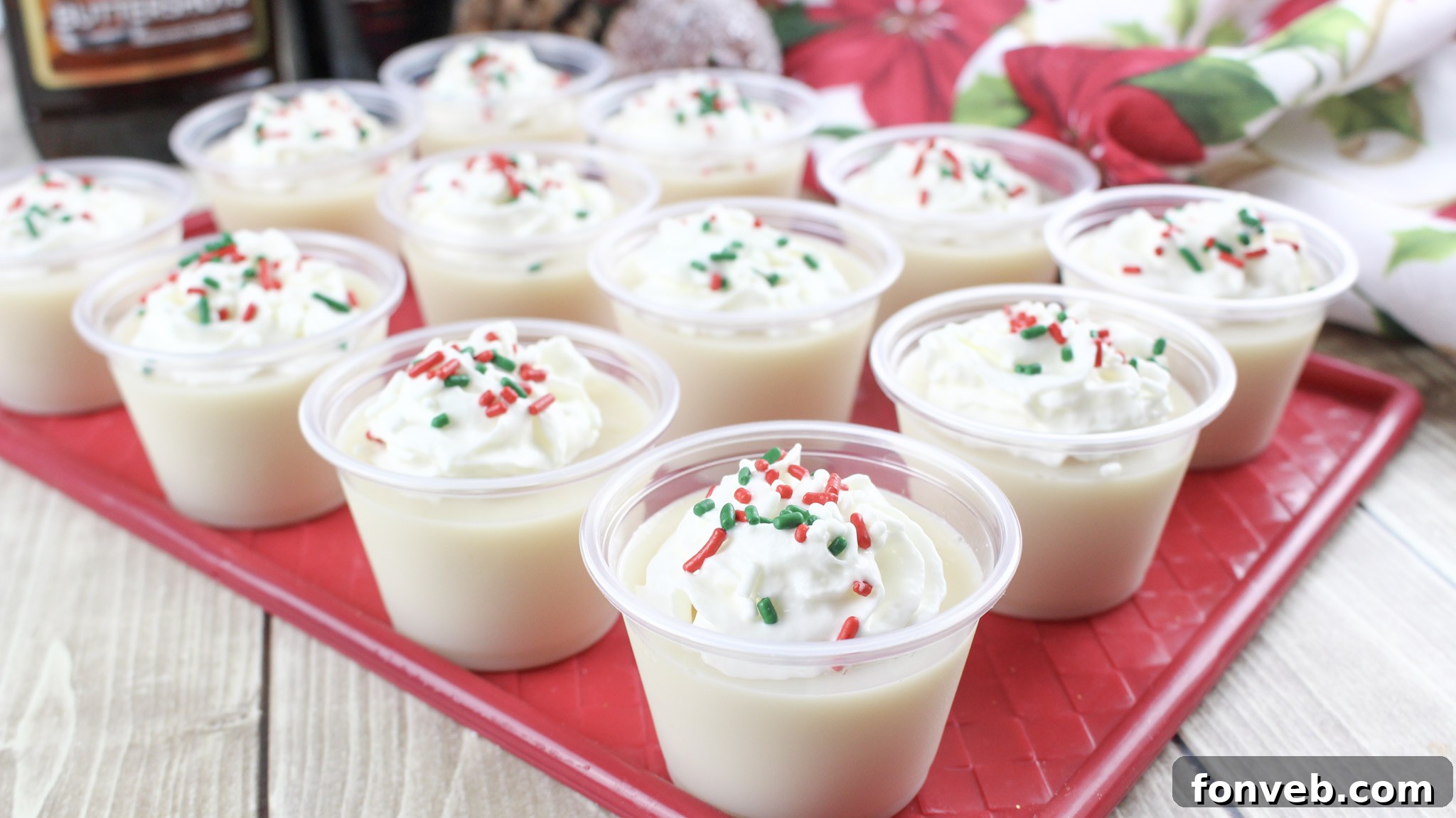 A single Christmas Sugar Cookie Jello Shot, beautifully presented with a dollop of whipped cream and colorful sprinkles.