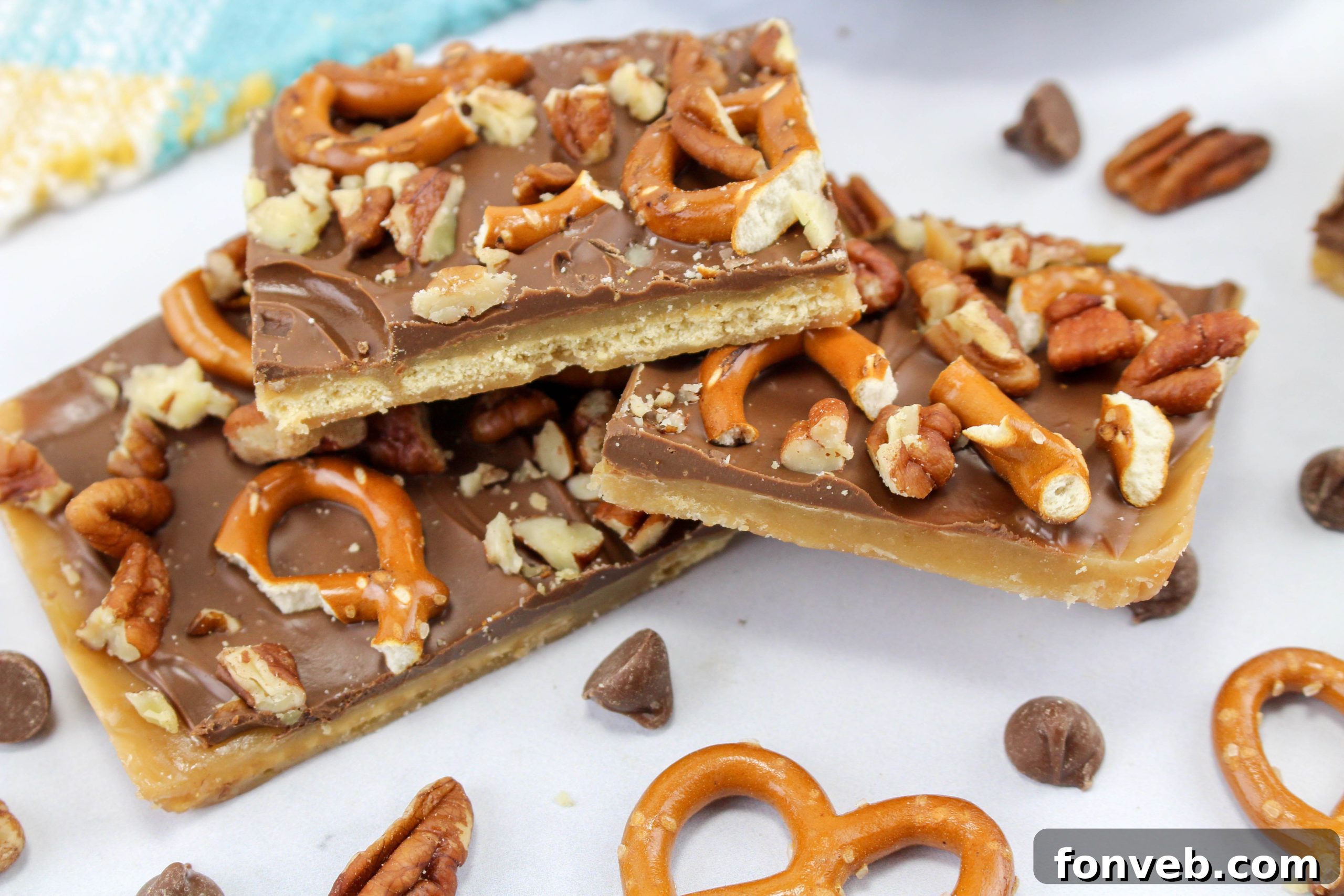 Delicious square pieces of Saltine Cracker Toffee, showcasing the layers of cracker, caramel, chocolate, pretzels, and pecans.