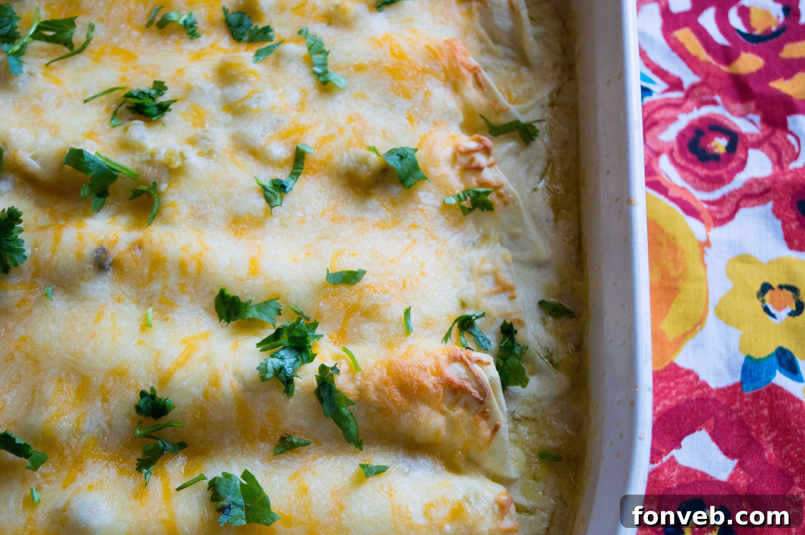 A serving of white chicken enchiladas fresh out of the oven, topped with more cheese and ready to serve.