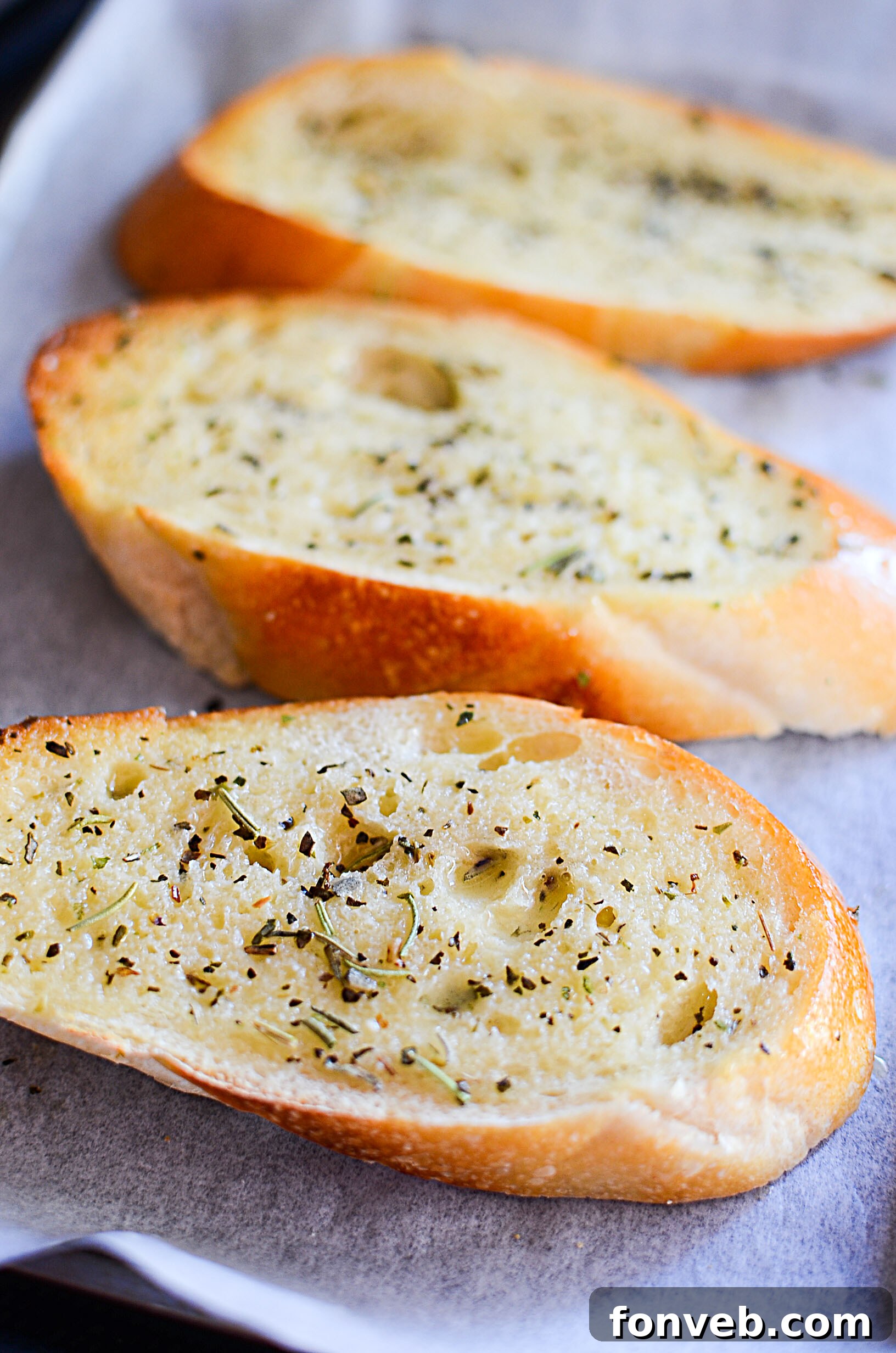 A stack of warm garlic bread slices, freshly baked, with melted parmesan cheese on top