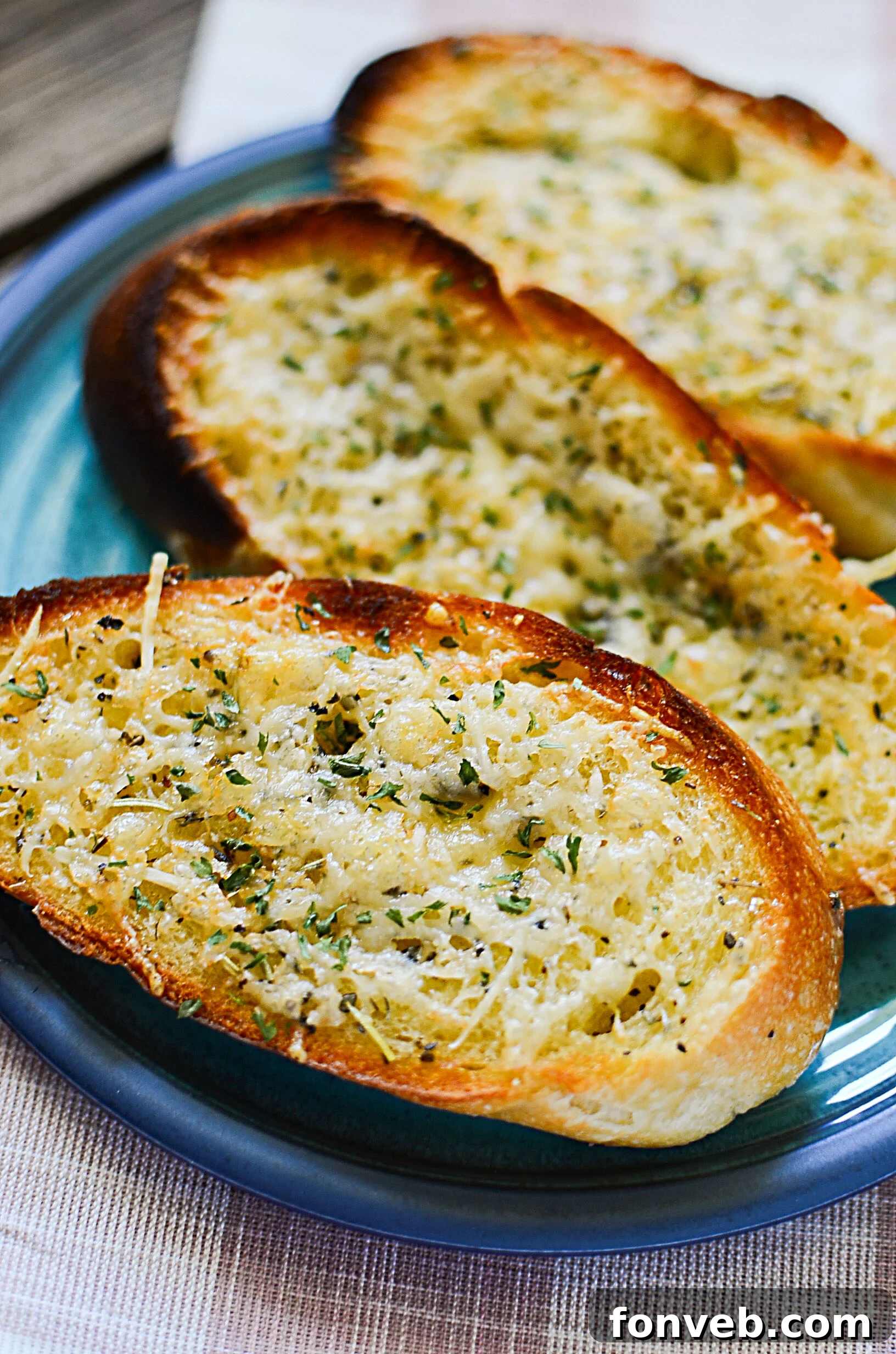 Seven slices of freshly made garlic parmesan bread, golden and crispy, on a serving plate
