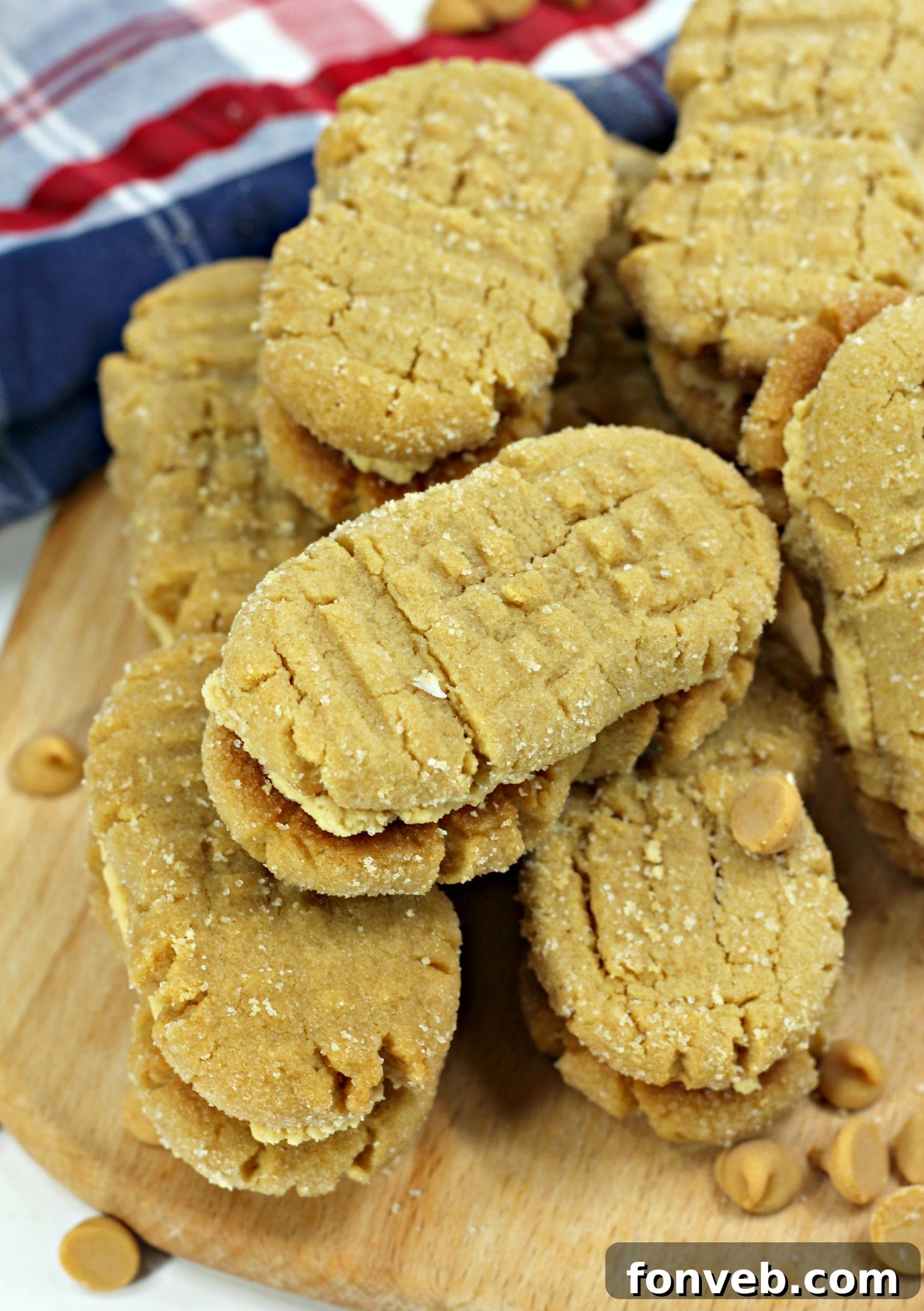 Hands shaping peanut butter cookie dough into a peanut likeness and pressing classic fork indentations onto the surface.
