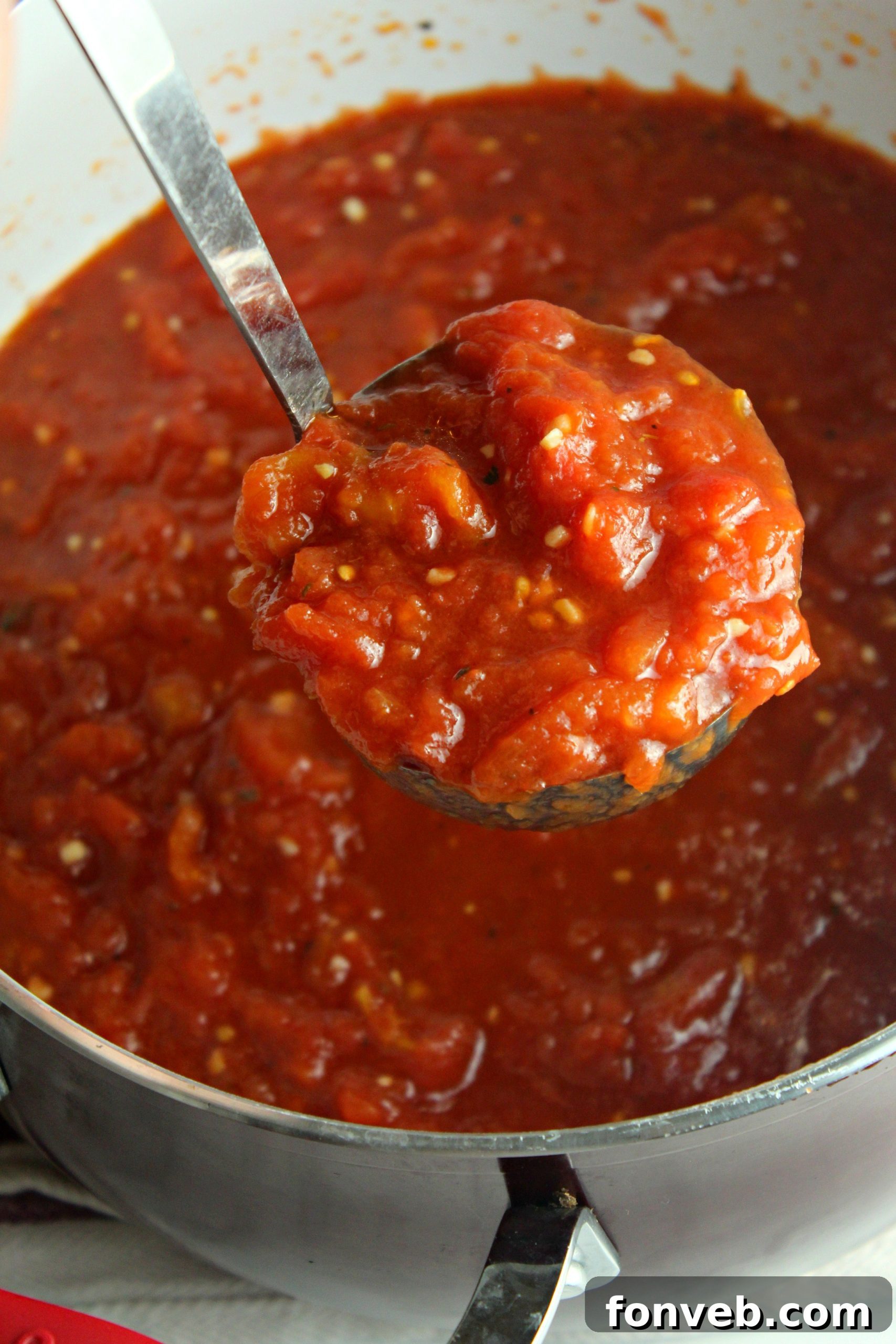 A large pot of homemade Italian tomato sauce simmering on the stove, surrounded by fresh ingredients like basil and tomatoes.