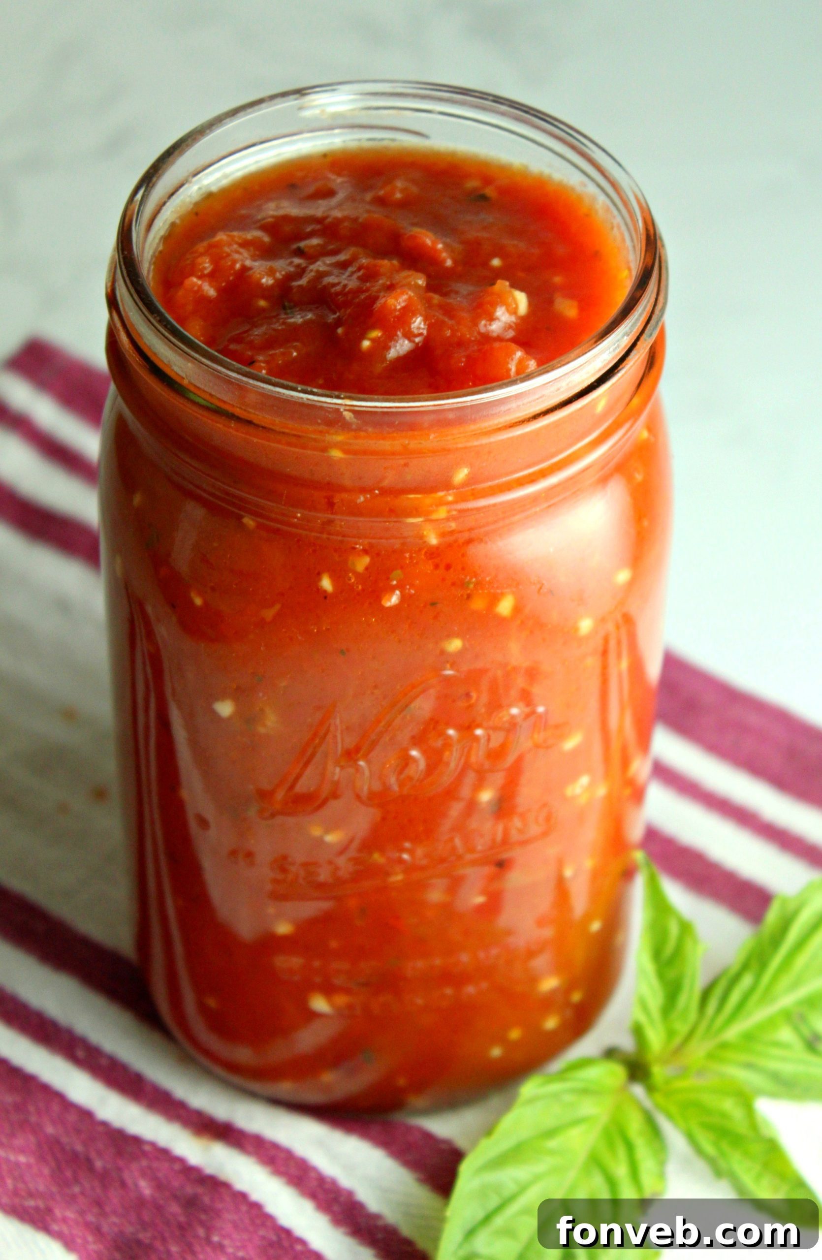 A close-up of a rustic wooden spoon stirring rich, red Italian tomato sauce in a pot.
