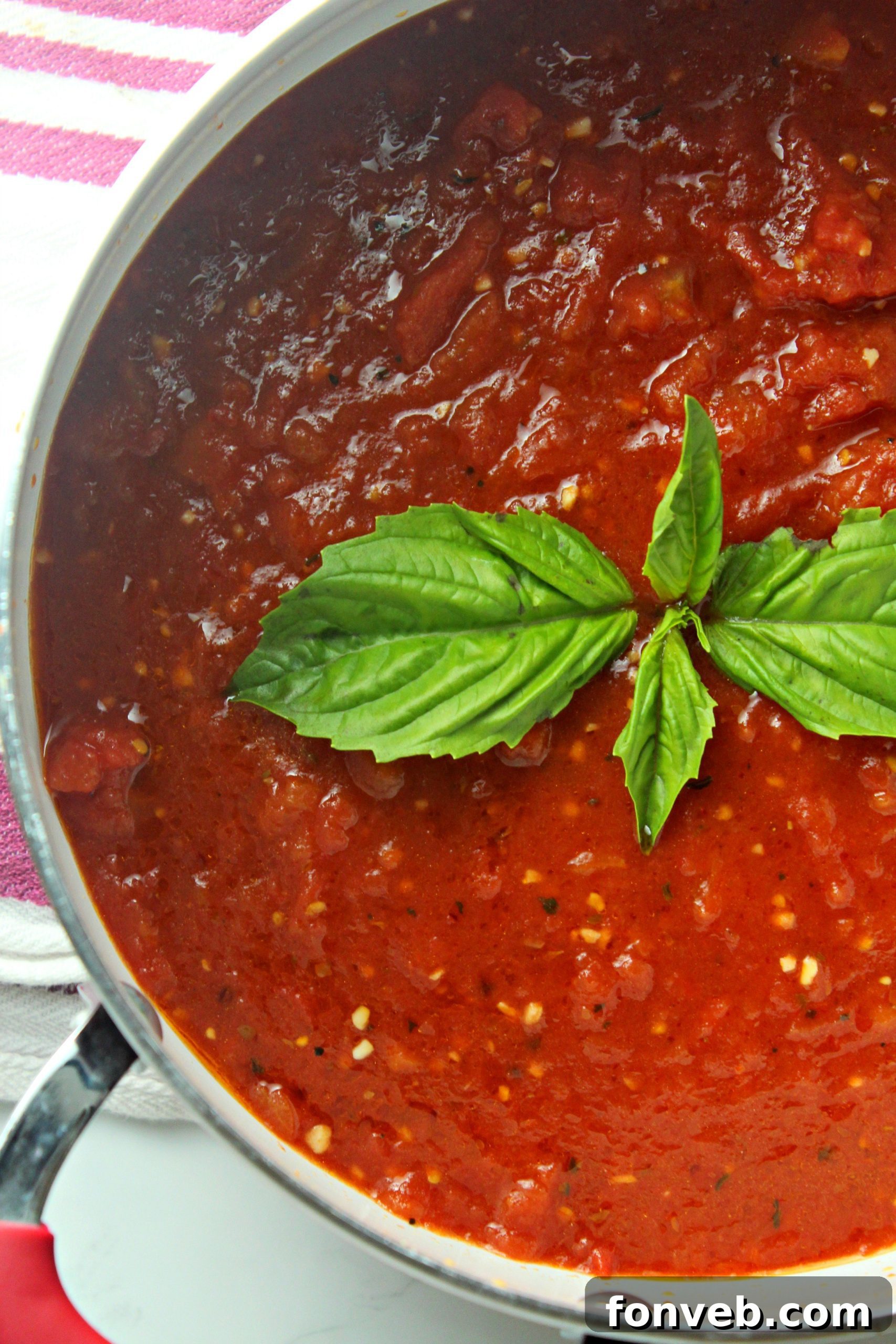 Fresh ingredients like garlic, onion, and spices arranged around a can of quality tomatoes.