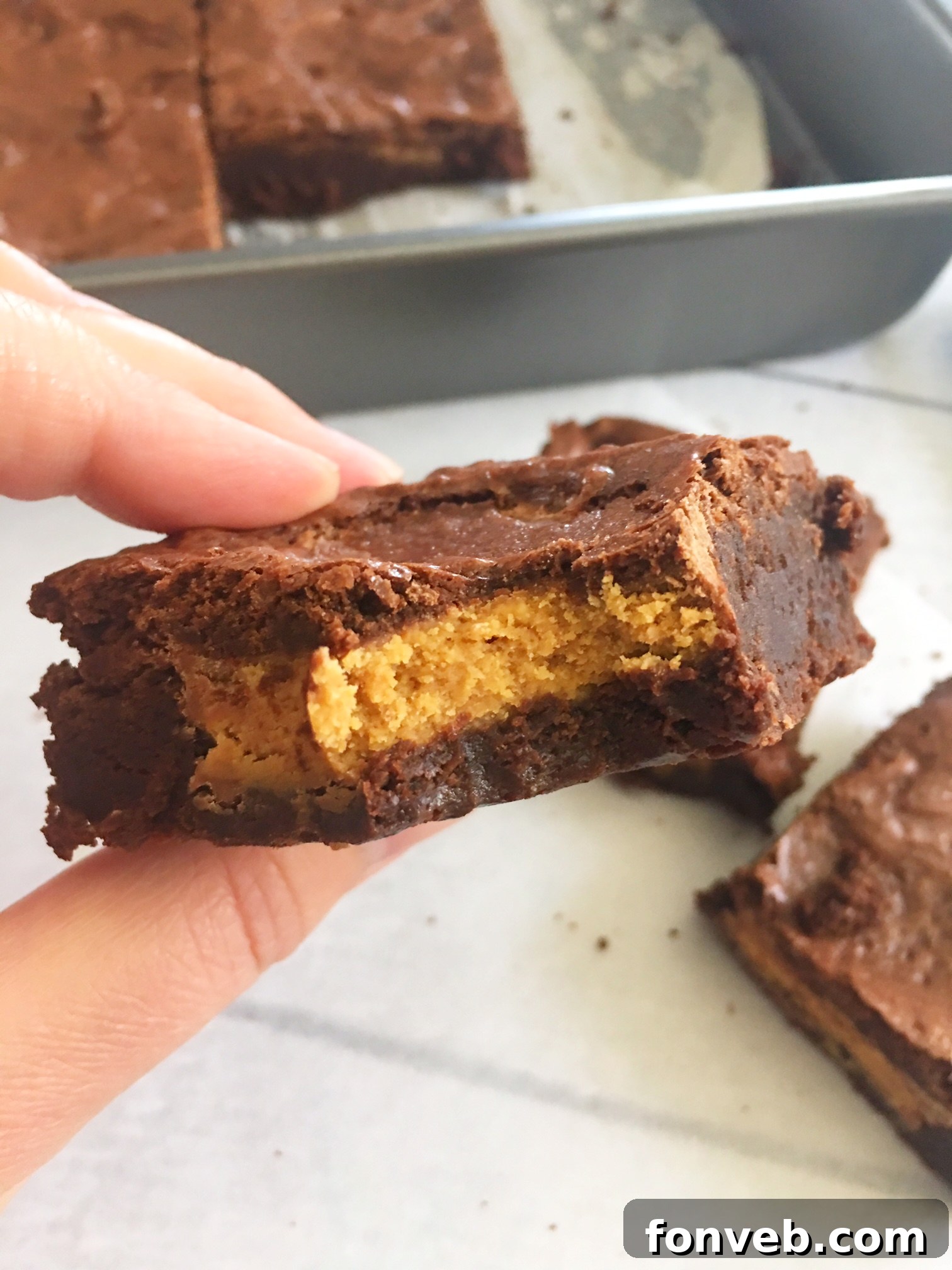 A vertical shot of Reese's Peanut Butter Cup Brownies, emphasizing their height and abundant peanut butter cups.