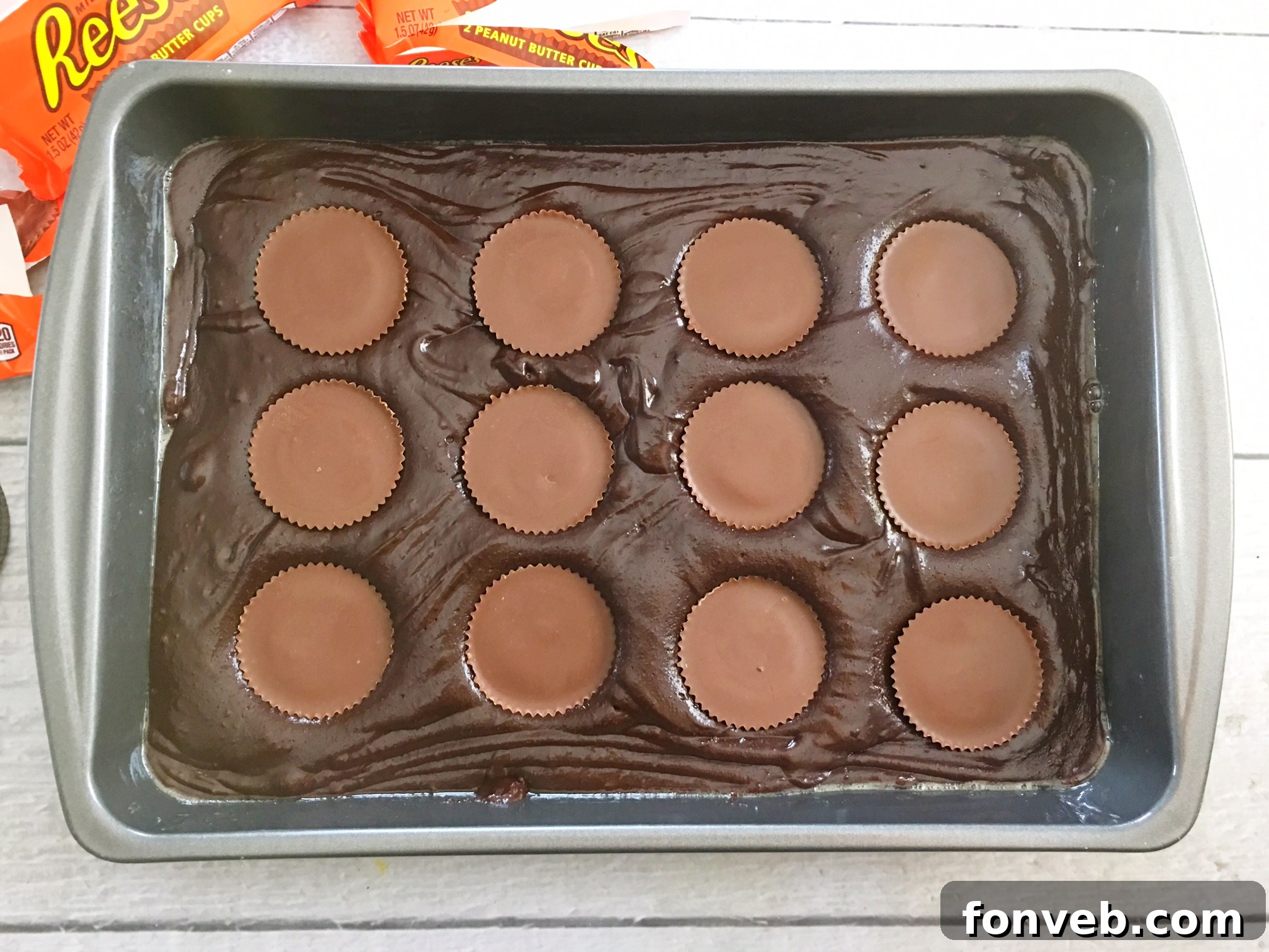 A tray of glistening, ultra-fudgy Reese's Peanut Butter Cup Brownies, fresh out of the oven, with a fork ready to dig in.