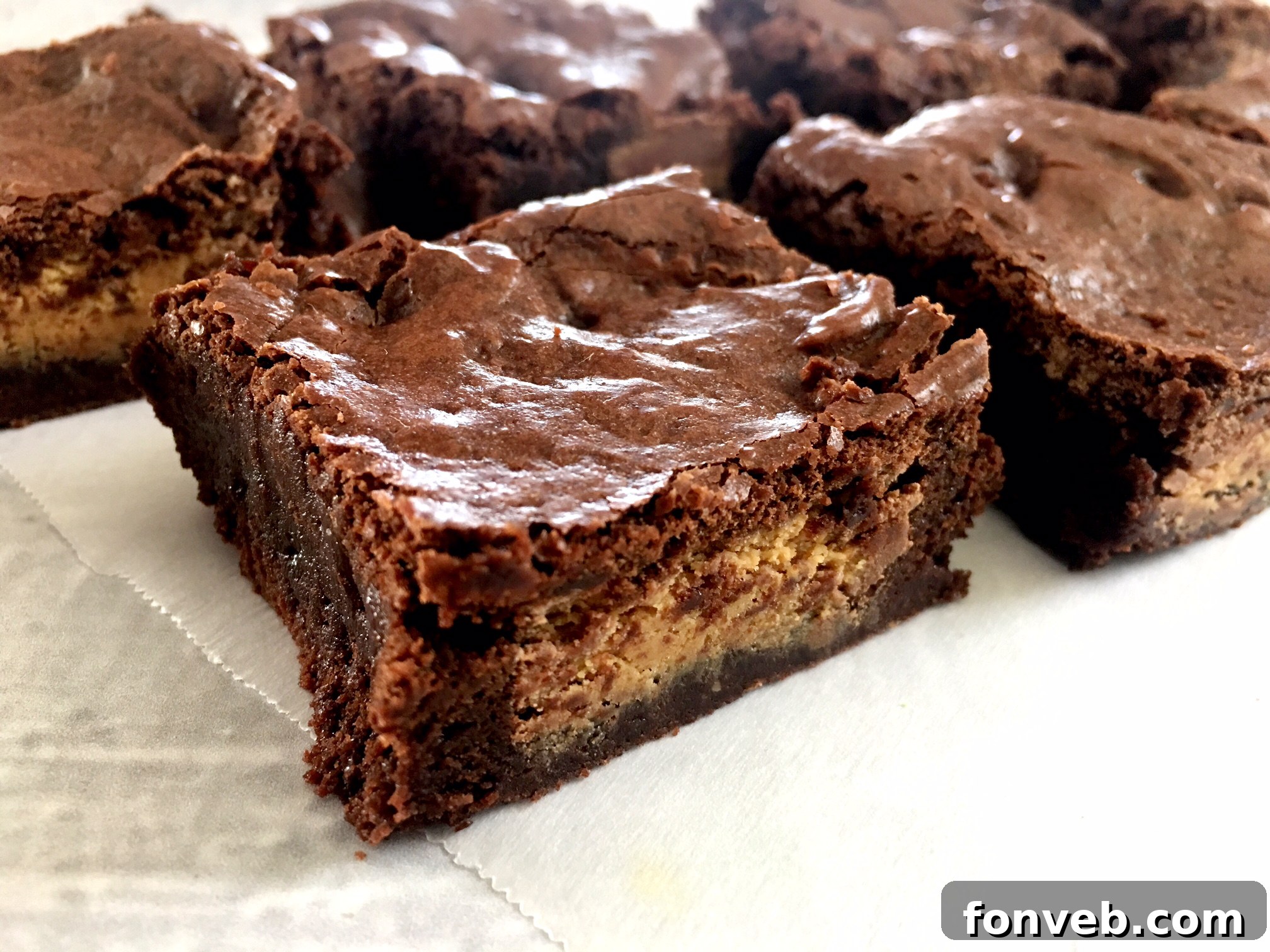 A close-up shot of a Reese's Peanut Butter Cup Brownie, with a segment cut out, showing its deep chocolate color and the distinct peanut butter cup inside.