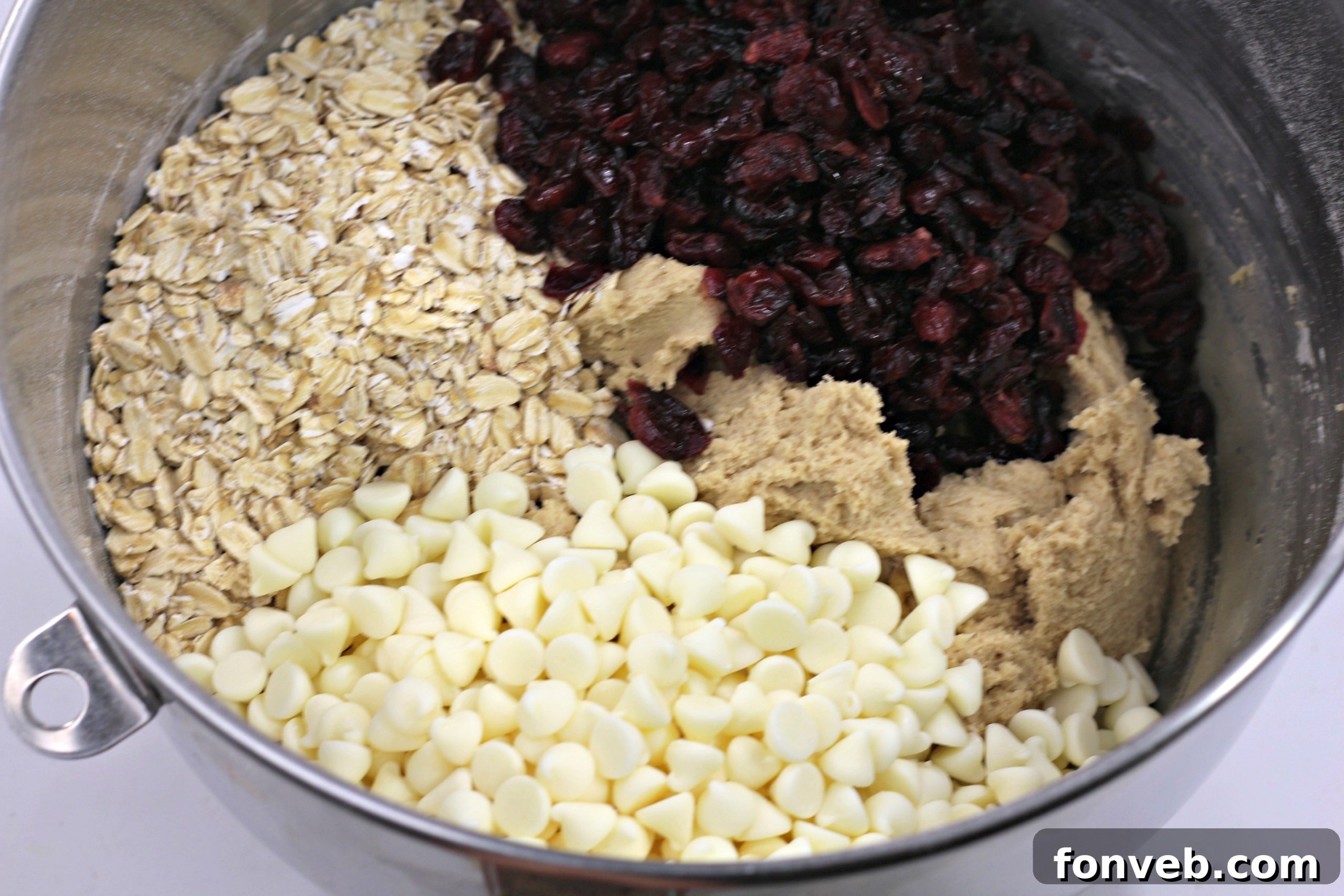 A stack of golden-brown Cranberry White Chocolate Oatmeal Cookies, sprinkled with festive snow-like sugar.