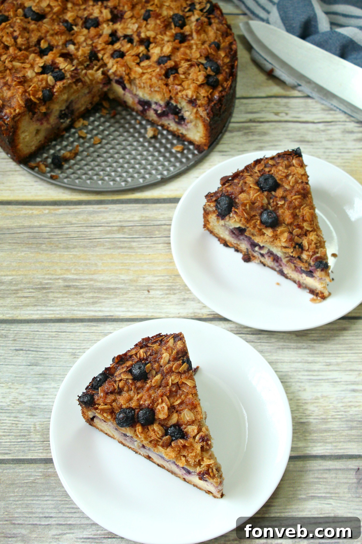 An appetizing overhead shot of the coffeecake, showcasing an abundance of juicy blueberries nestled within the creamy filling and a generous sprinkle of golden oat streusel.