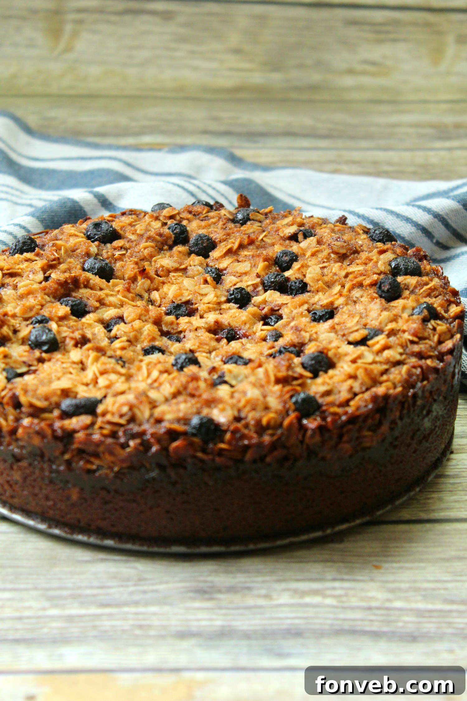 A serving of blueberry cream cheese coffeecake on a plate, showcasing its beautiful layers – the tender cake, creamy filling, and scattered blueberries, topped with golden streusel.