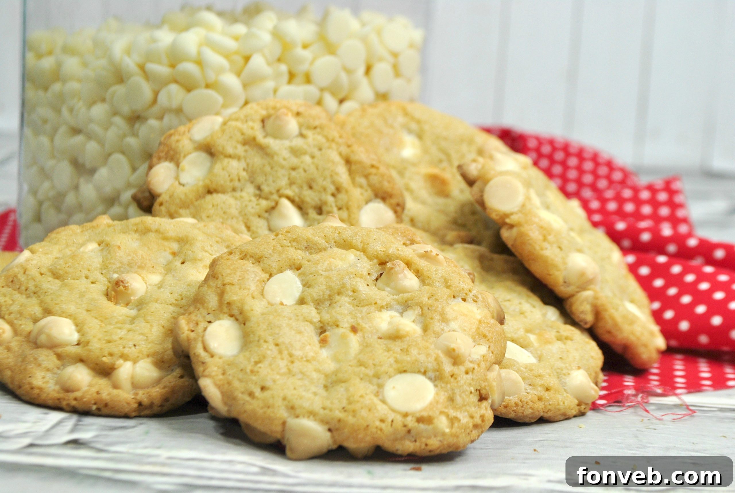 A stack of golden Root Beer Float Cookies, with visible white chocolate chips, on a rustic wooden surface.