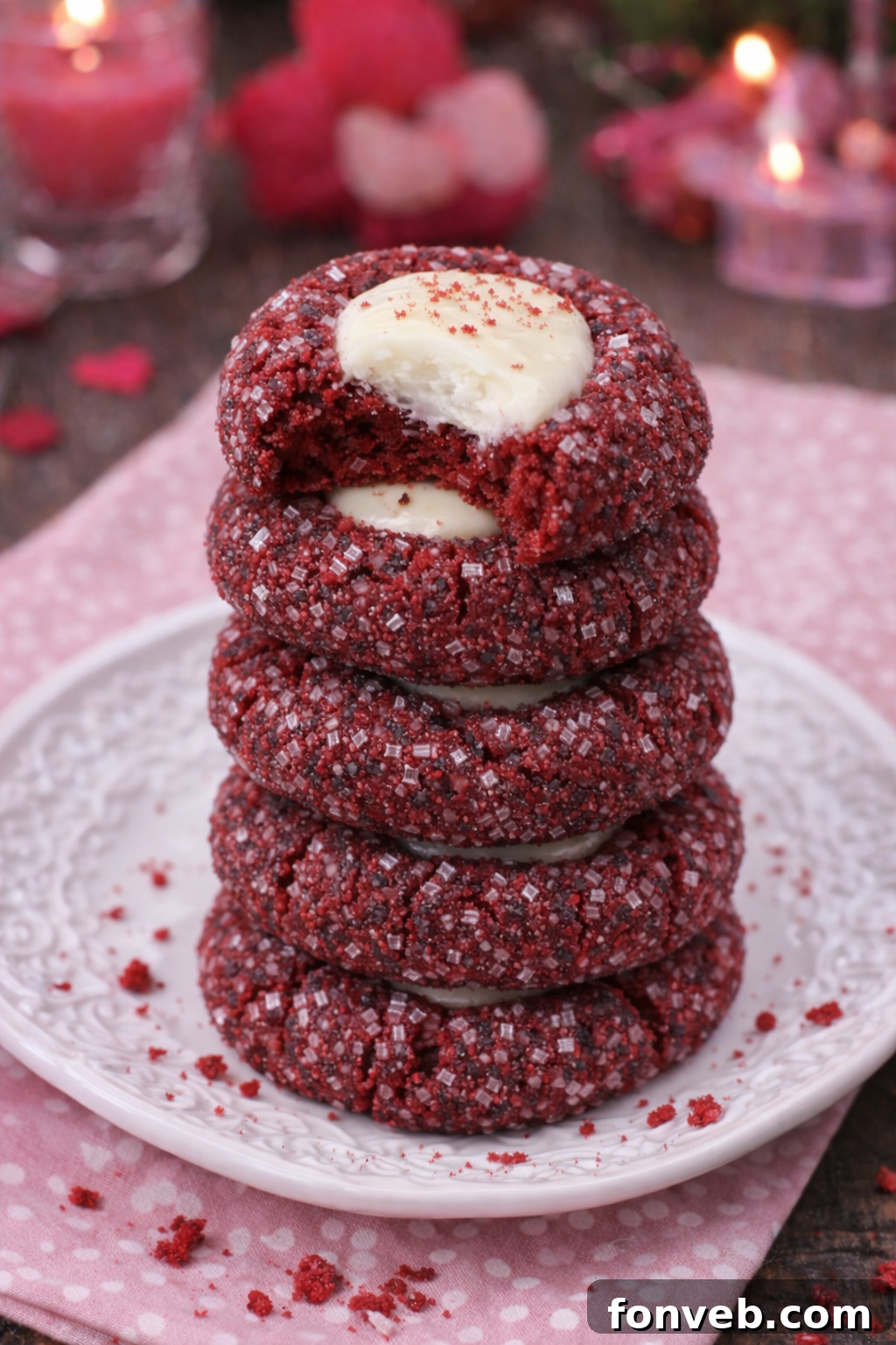 Stack of Red Velvet Cheesecake Thumbprint Cookies with a bite taken from the top one, showcasing the creamy filling