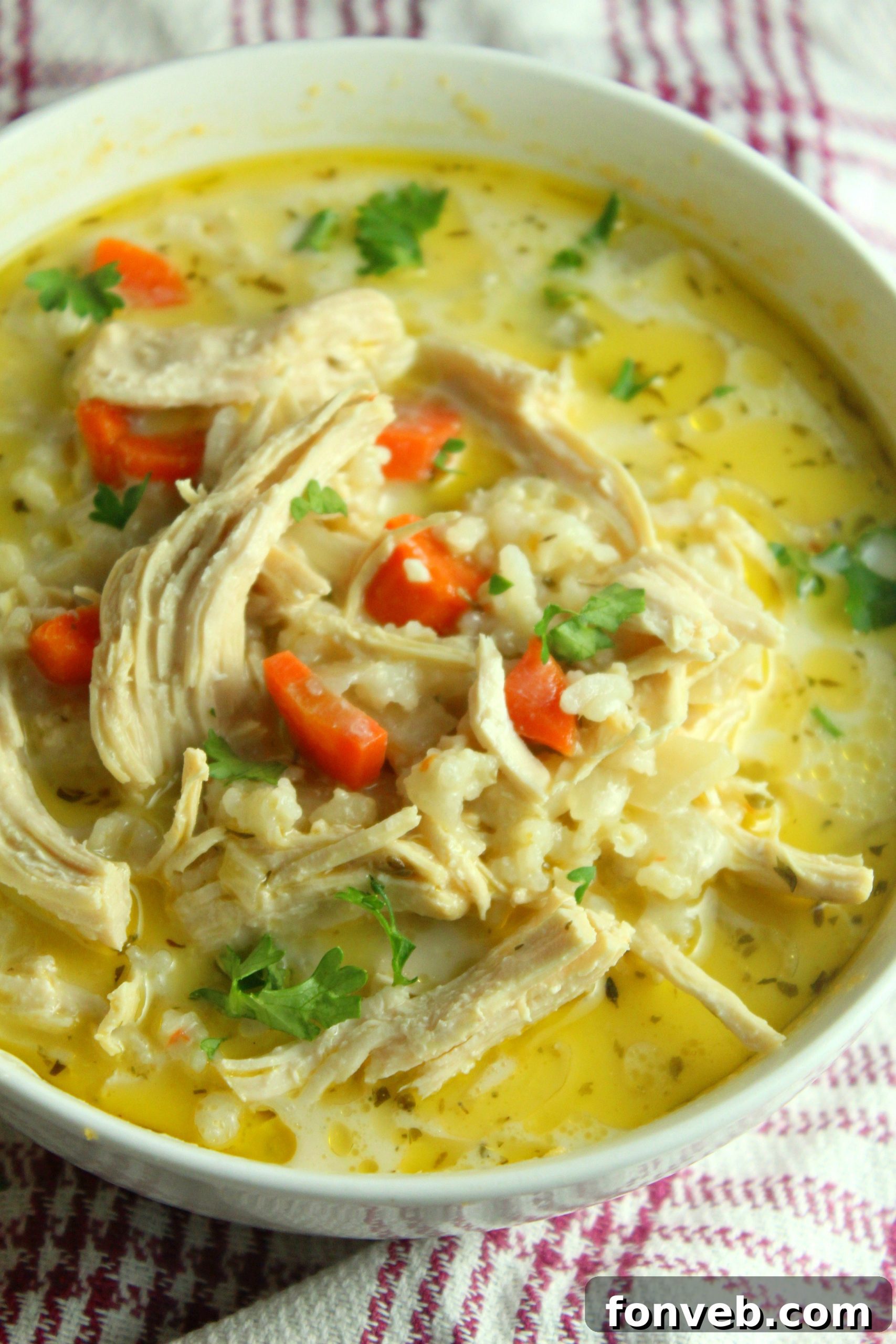 Overhead shot of a bowl of chicken and rice soup with a spoon, ready to be enjoyed.