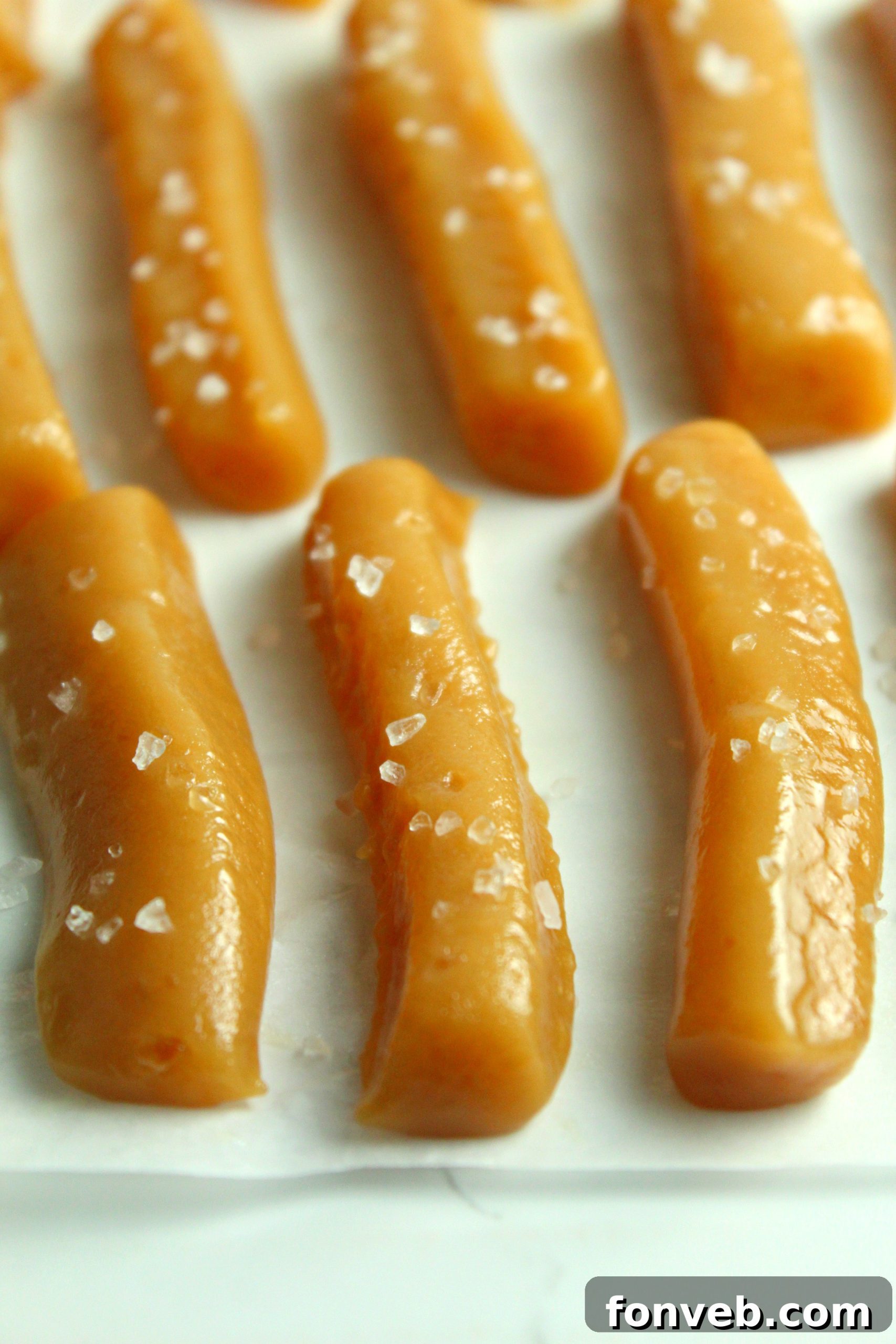 Handcrafted Salted Caramel Bliss 3 Freshly cut squares of homemade salted caramels on parchment paper.