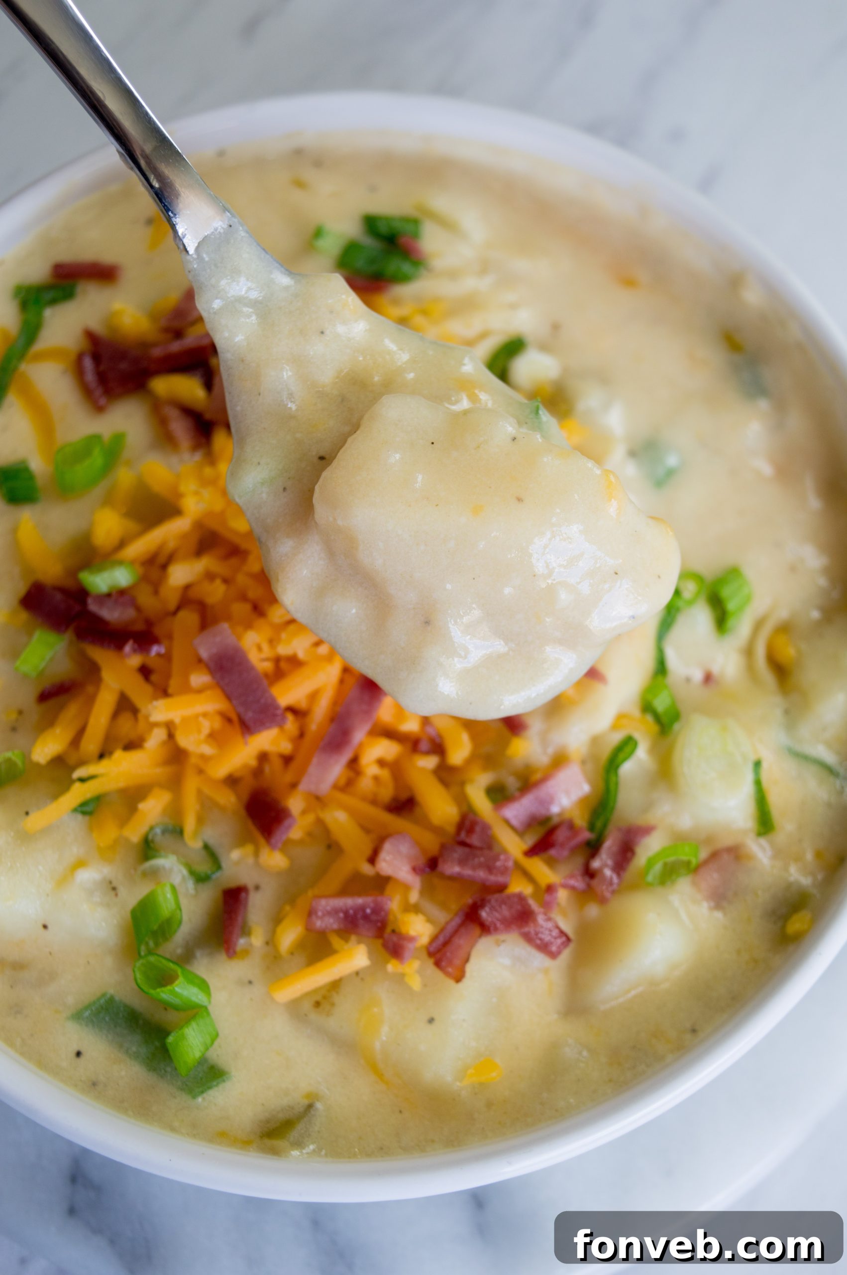 Another enticing photo of loaded potato soup, highlighting the generous toppings of bacon, cheese, and green onions.